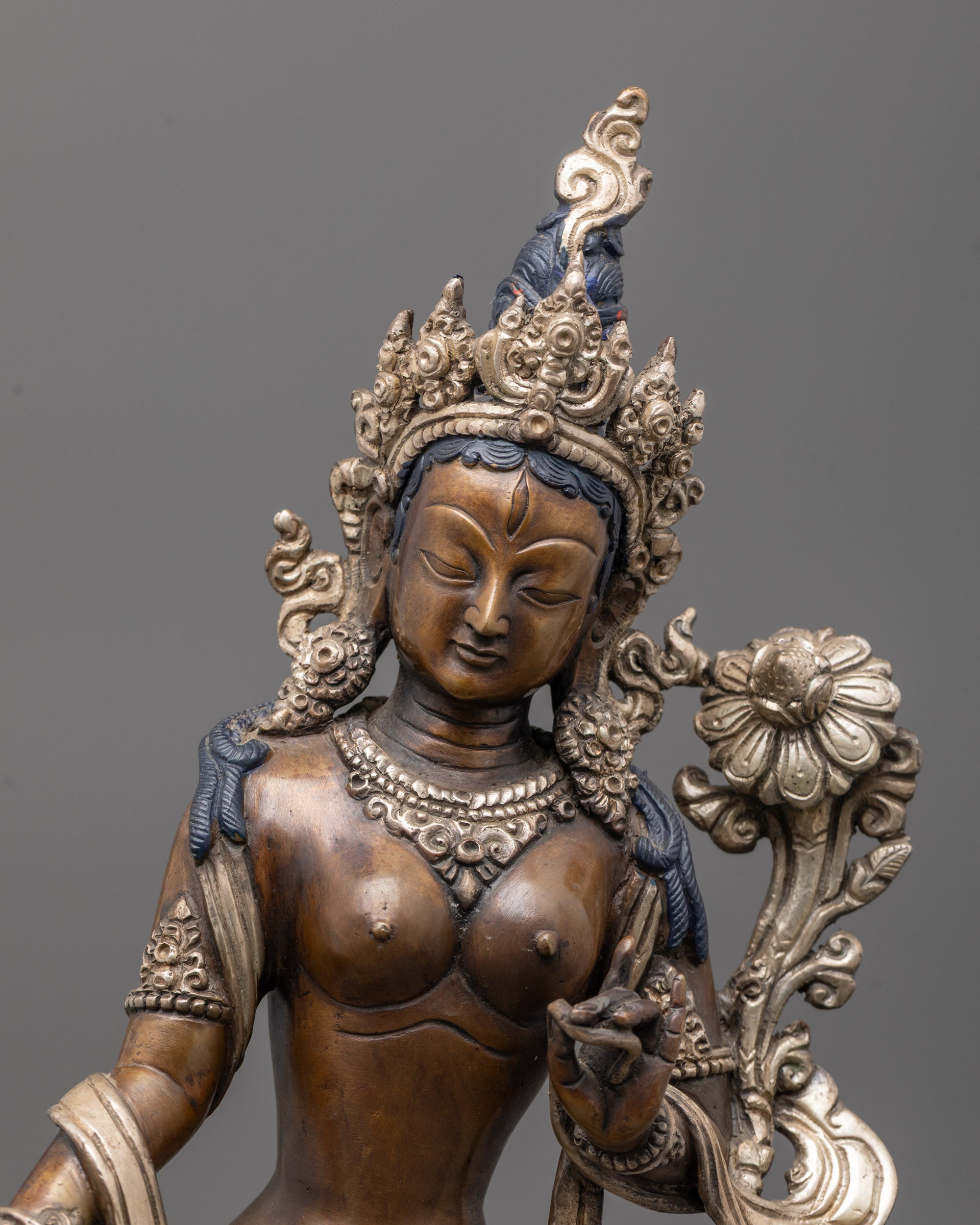Close up of silver-plated jewelry and flowing garments on oxidized copper Green Tara statue