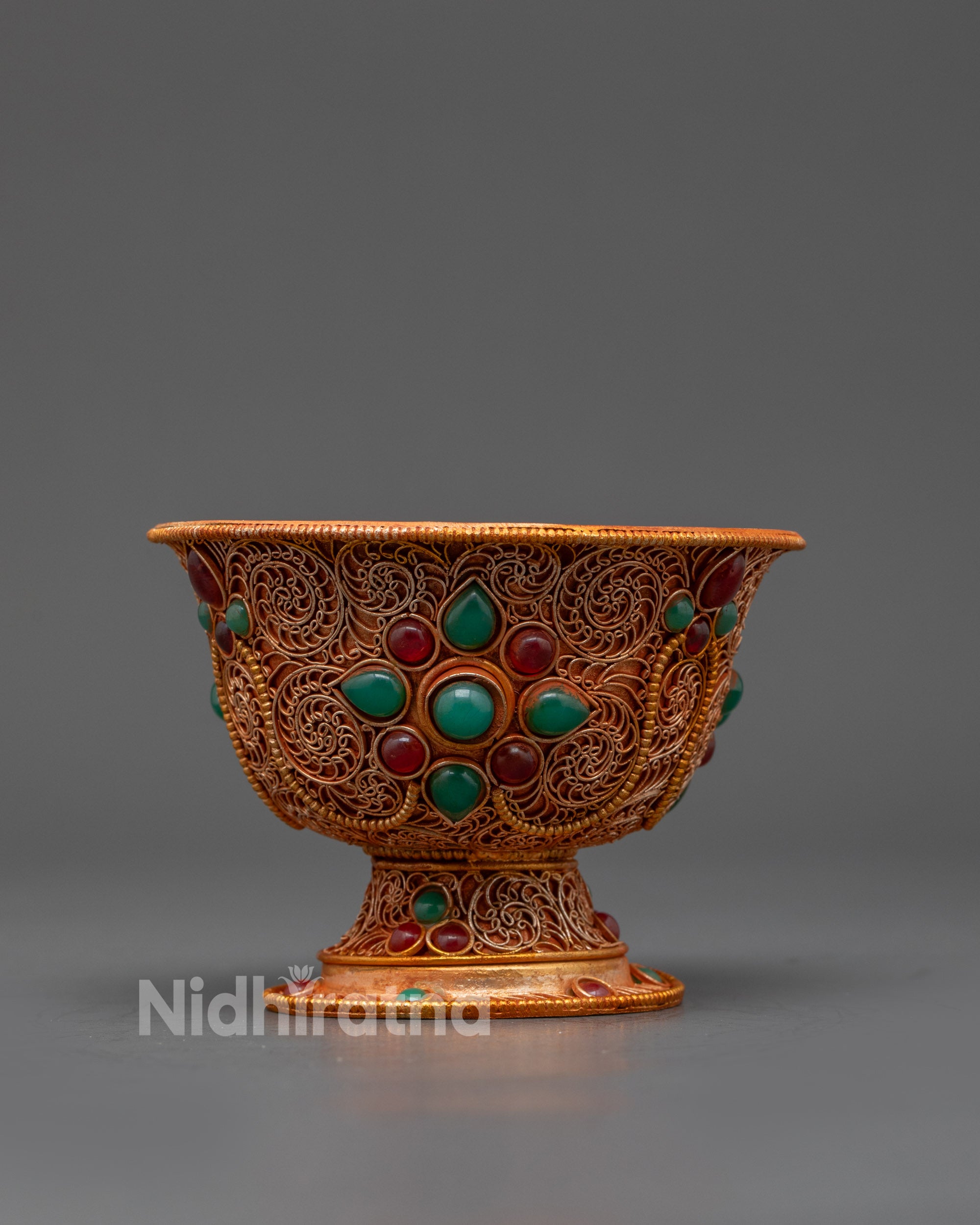 Close up of single Tibetan water offering bowl showing floral semi-precious stones