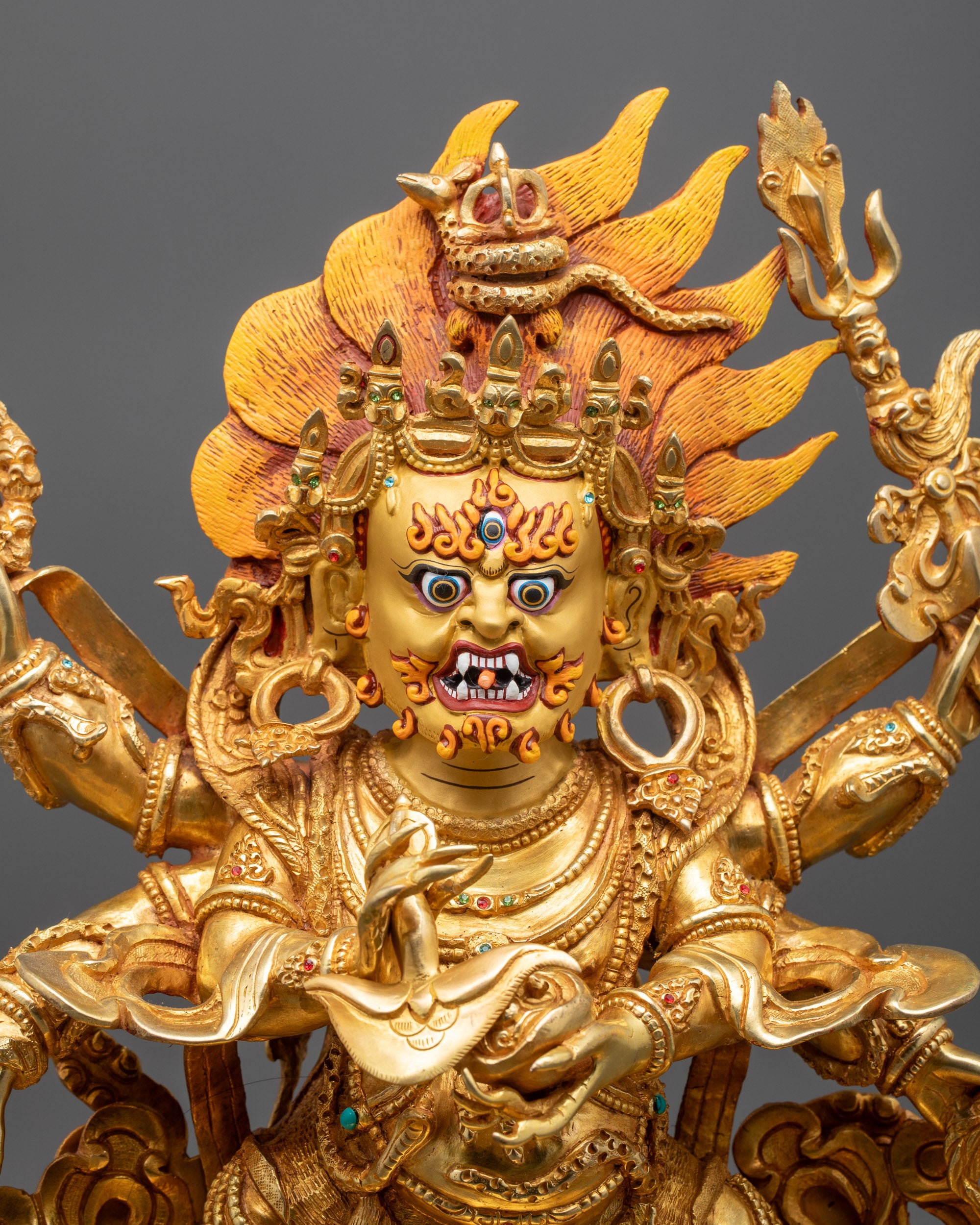 Close up of six arms holding trident hook skull cup curved knife and damahru
