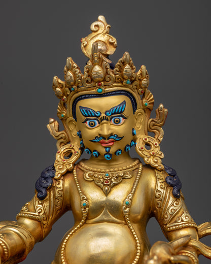 Close up of the gold gilded Dzambhala statue seated on lotus in royal ease.