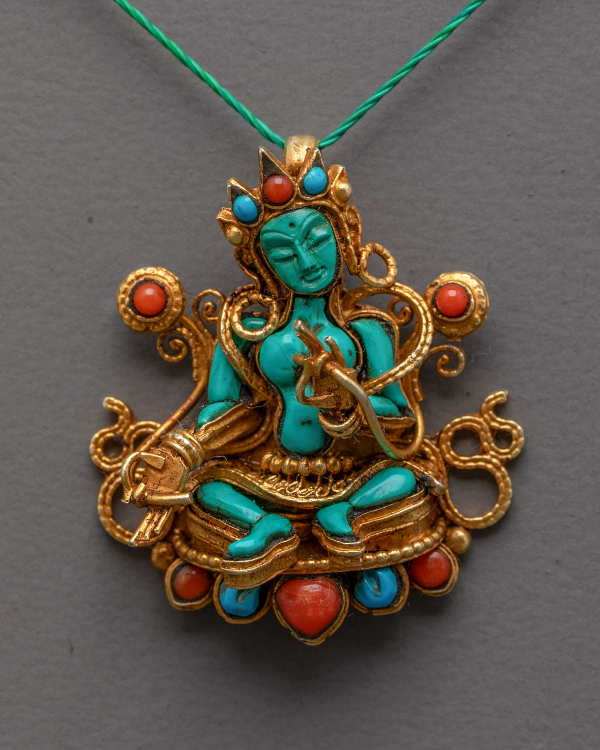 Close up of turquoise Green Tara seated in royal ease pose with semi-precious stones 