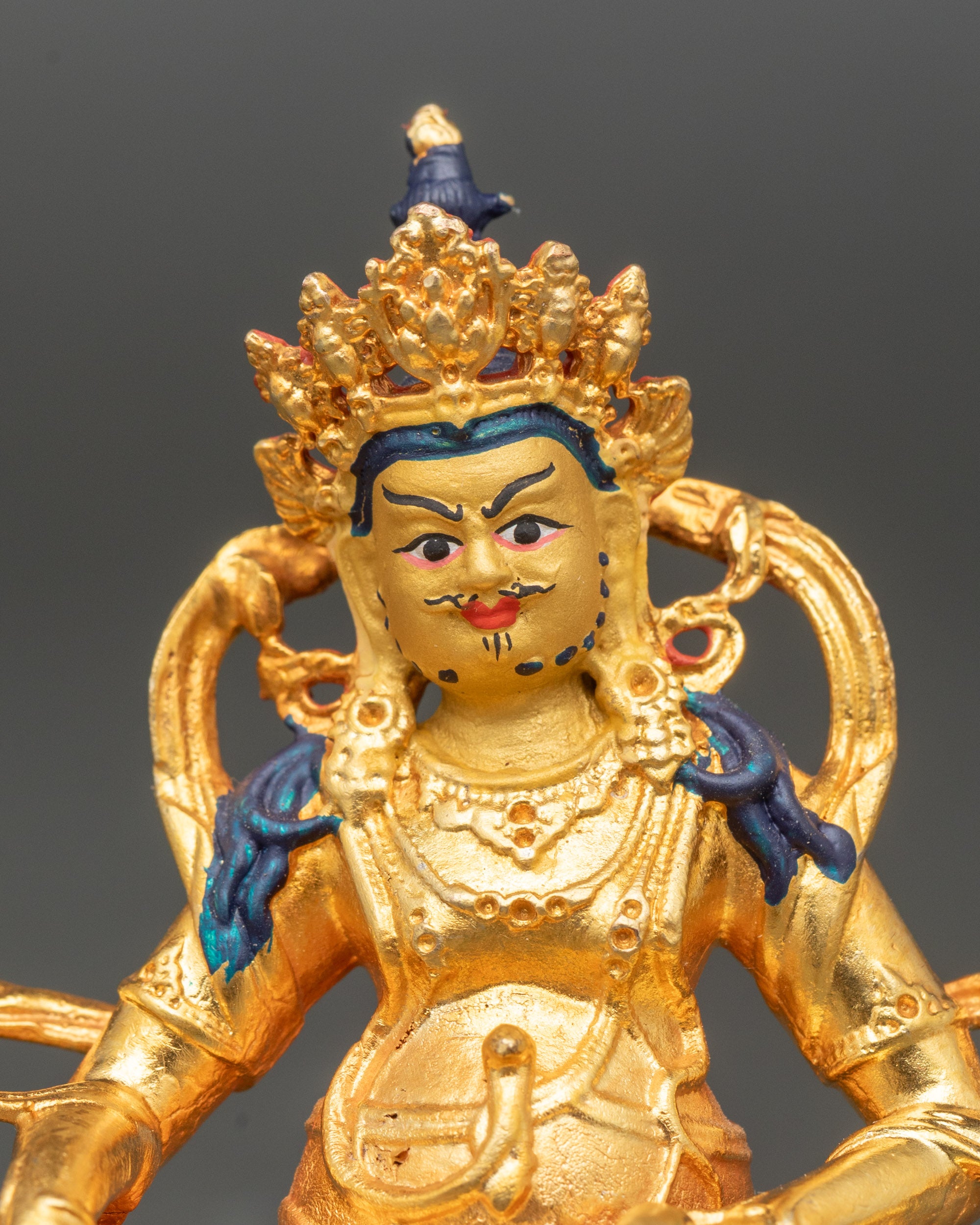 Close view of Dzambhala holding jewel-releasing mongoose and sacred citron fruit symbols of wealth