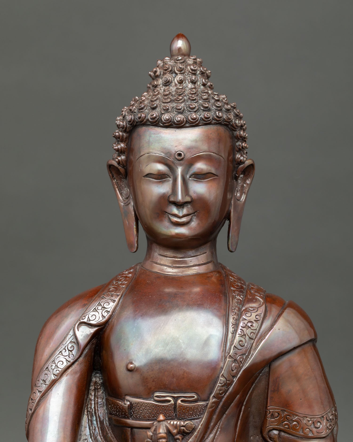 Close view of Shakyamuni Buddha face in oxidized copper with detailed craftsmanship, representing Himalayan Buddhist art and lotus throne design.