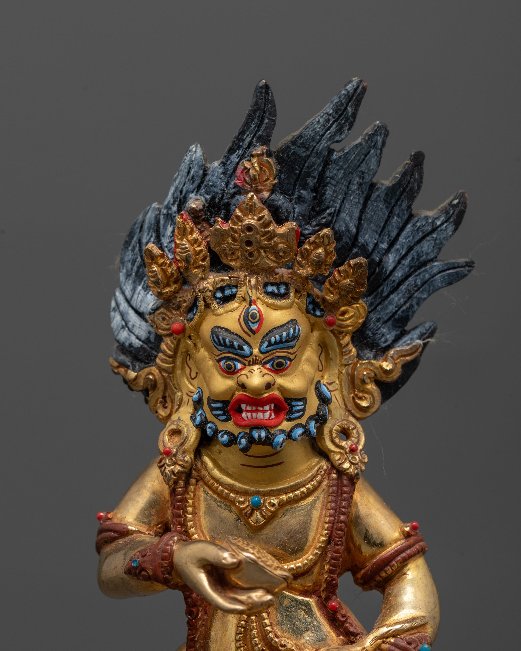 Closed-up Black Dzambhala deity statue crafted using lost wax method featuring gold gilding