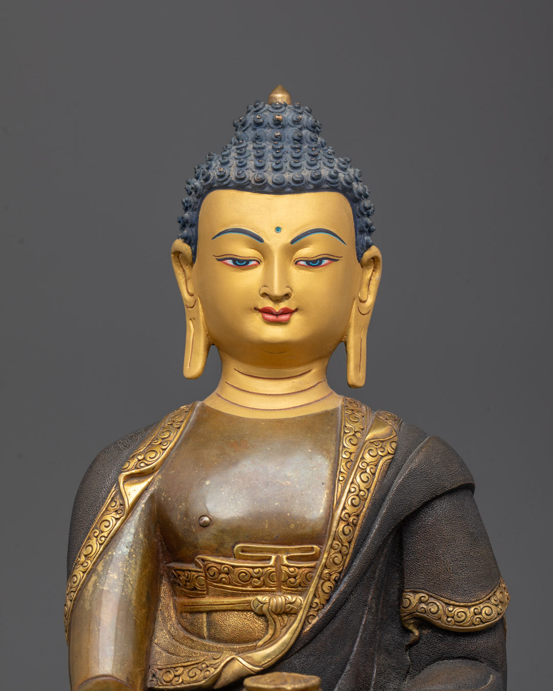Closeup of 24K gold gilded face and begging bowl on handcrafted Gautam Buddha sculpture