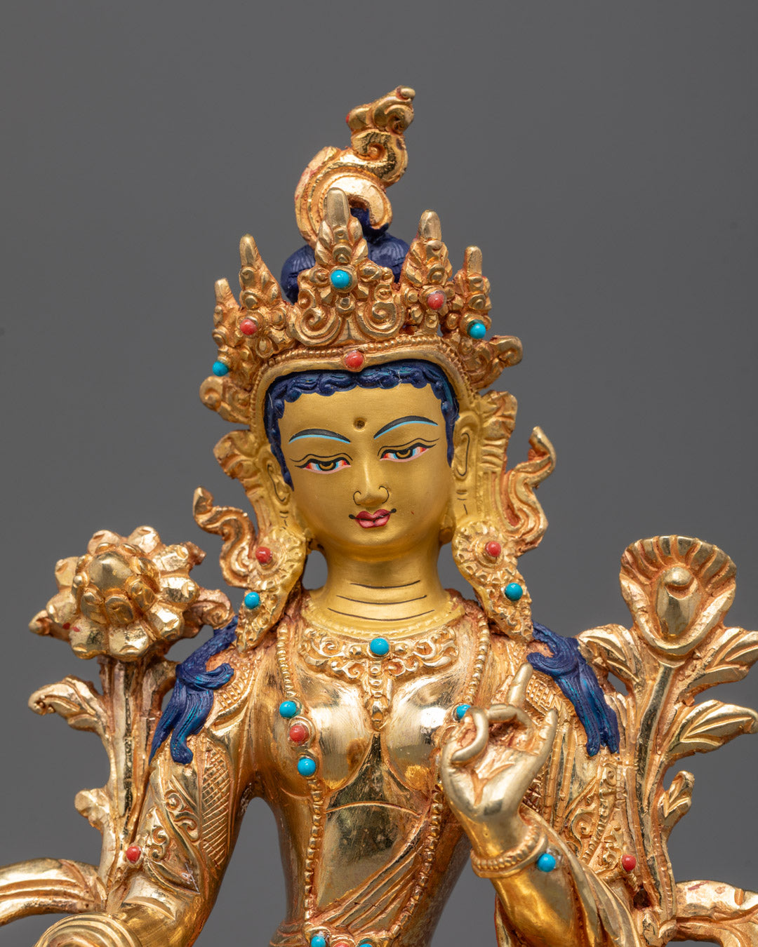 Closeup of Green Tara statue’s gold-gilded face and intricate semi-precious stones