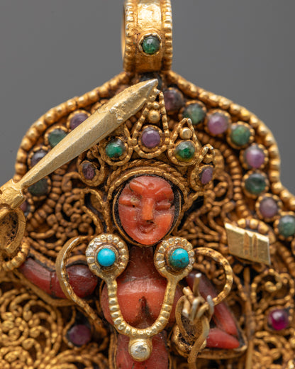Closeup of Manjushri Locket showing intricate filigree, red crystal deity holding sword, and semi-precious stones on gold-gilded pendant.