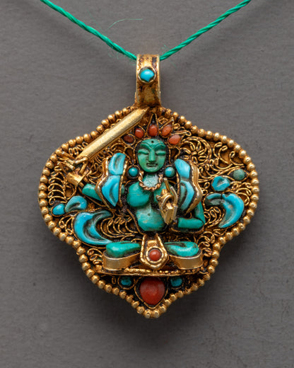 Closeup of Manjushri Locket showing intricate filigree work, green crystal deity, and semi-precious stones on a gold-gilded pendant.