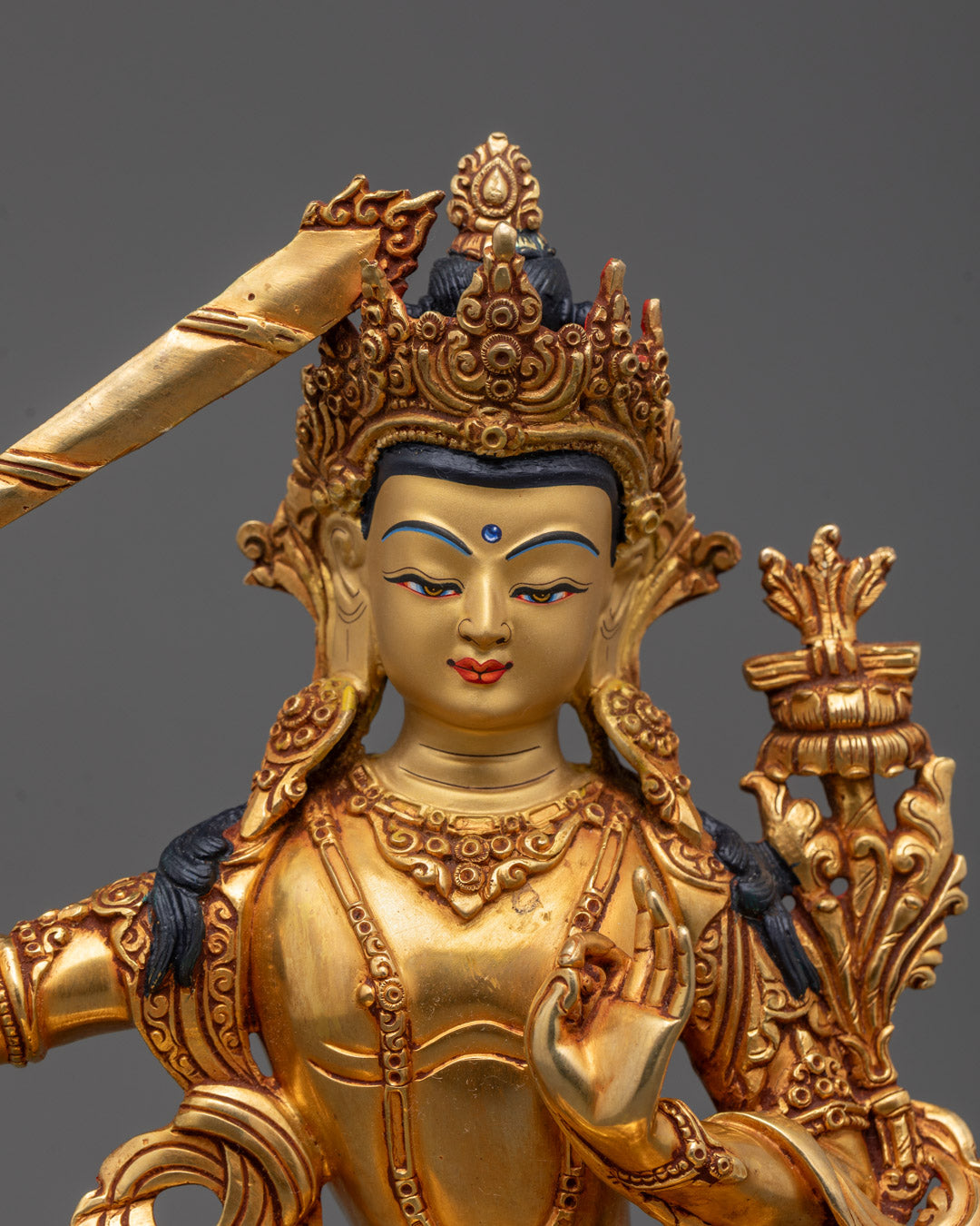 Closeup of Manjushri’s gold-fire gilded body holding Double-Edged Sword and utpala flower