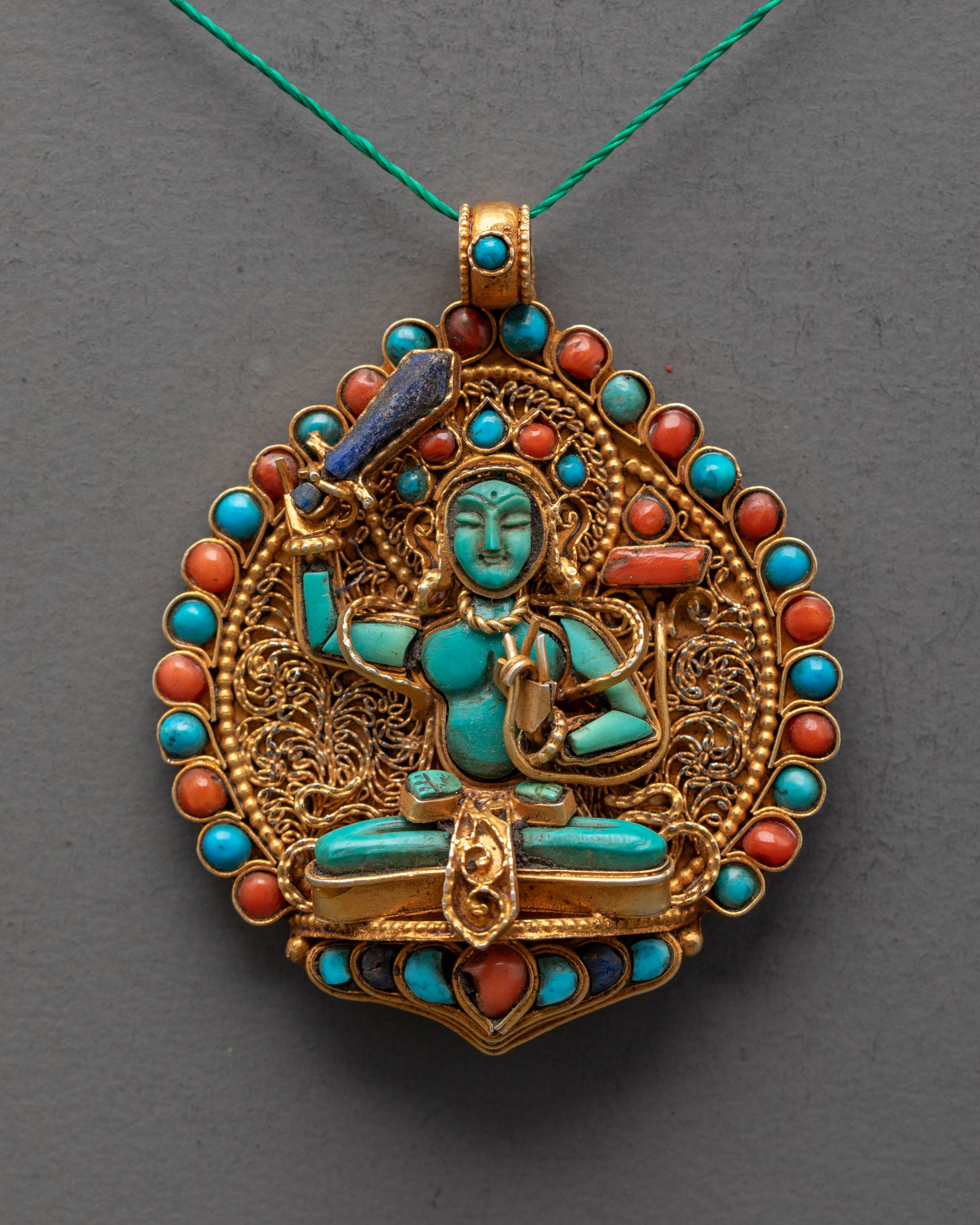 Closeup of handcrafted Manjushri pendant showing lapis sword and semi-precious stone details