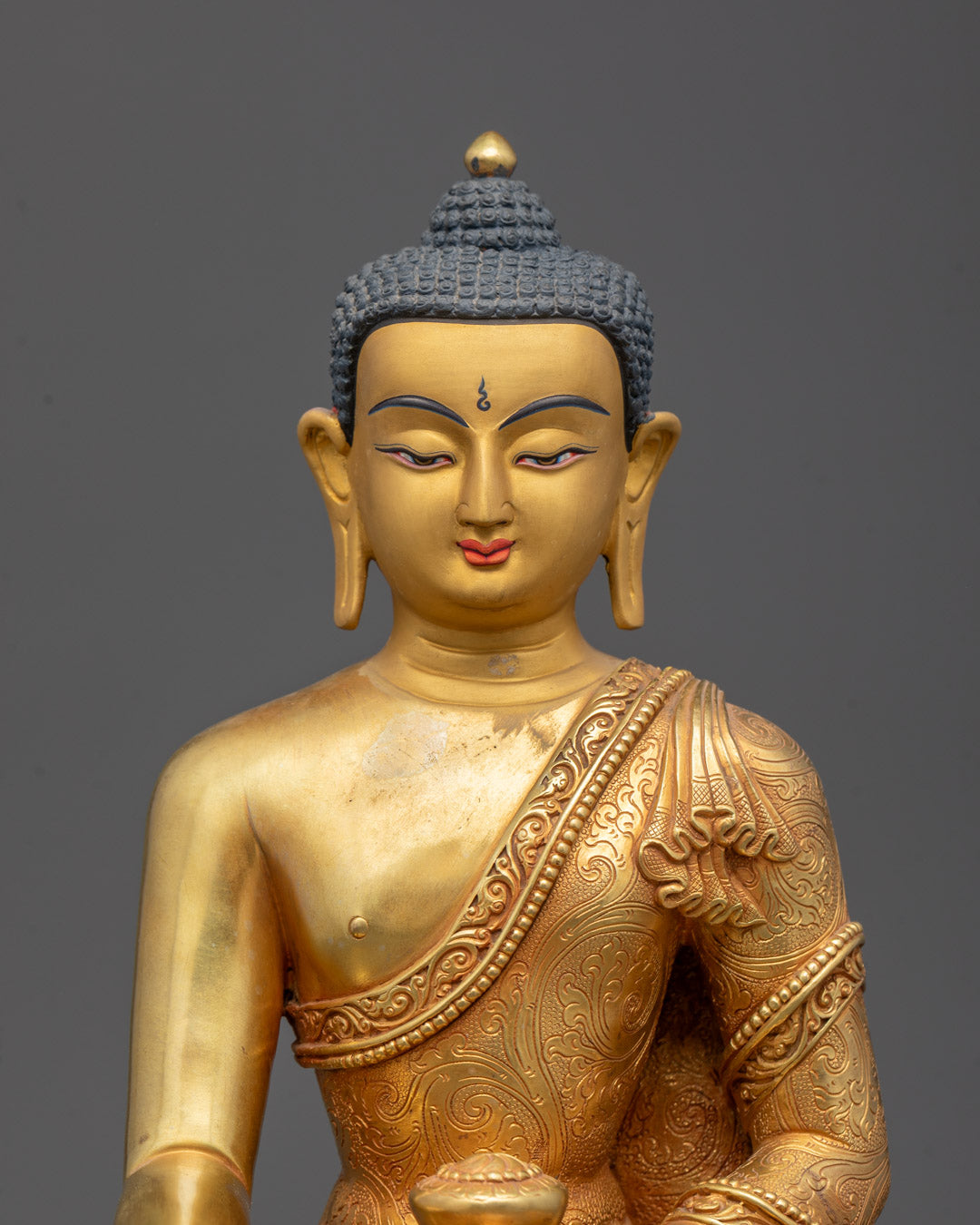 Closeup of intricate carvings on gold fire-gilded body of Shakyamuni Buddha statue