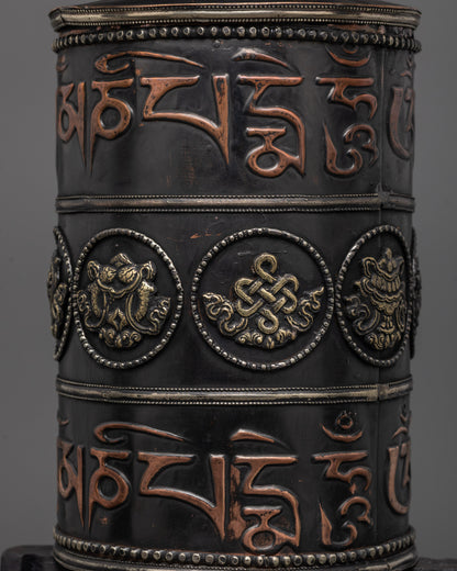 Dark wood-framed prayer wheel featuring engraved spiritual symbols and motifs