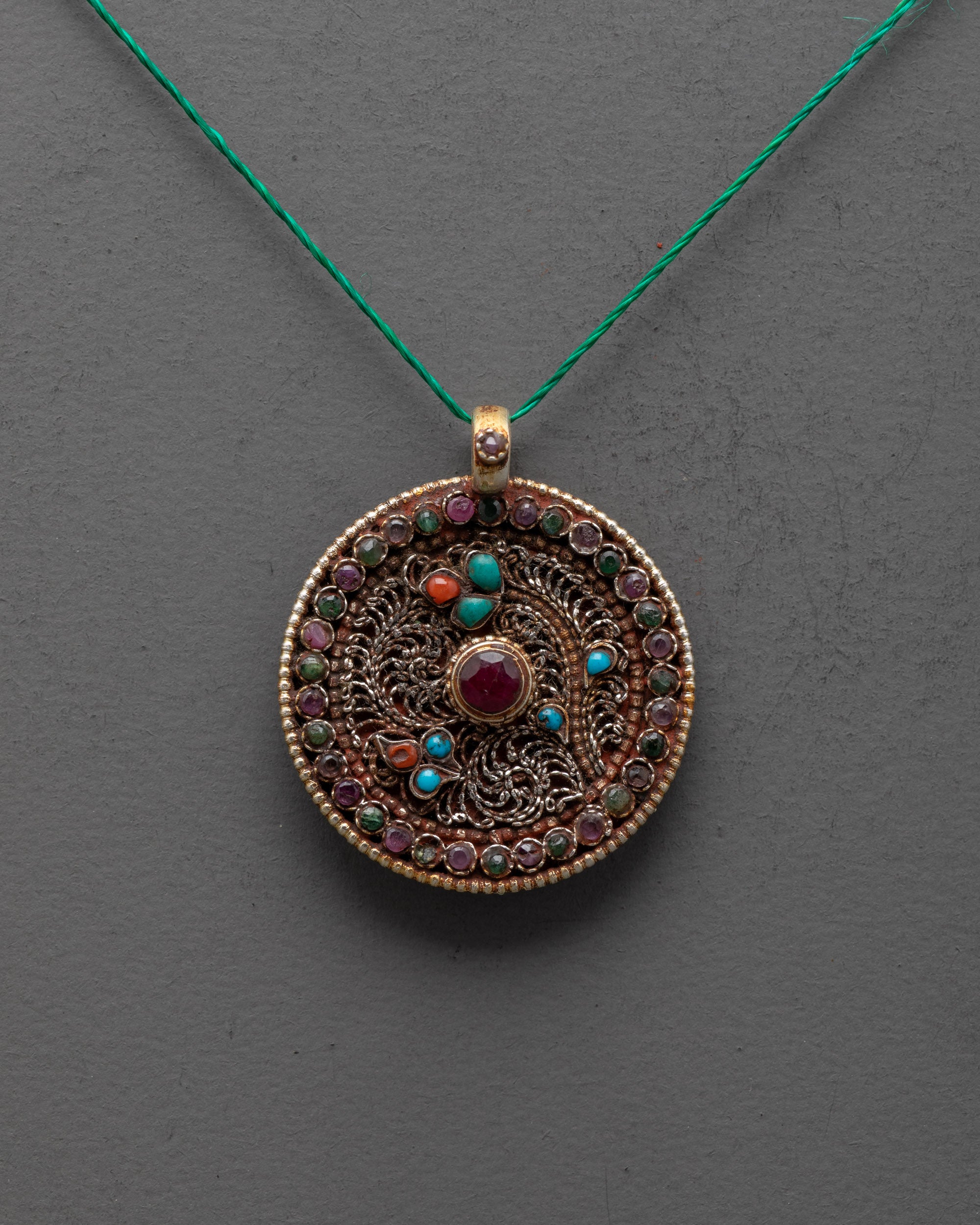 Decorative pendant necklace with gemstones on a gray background
