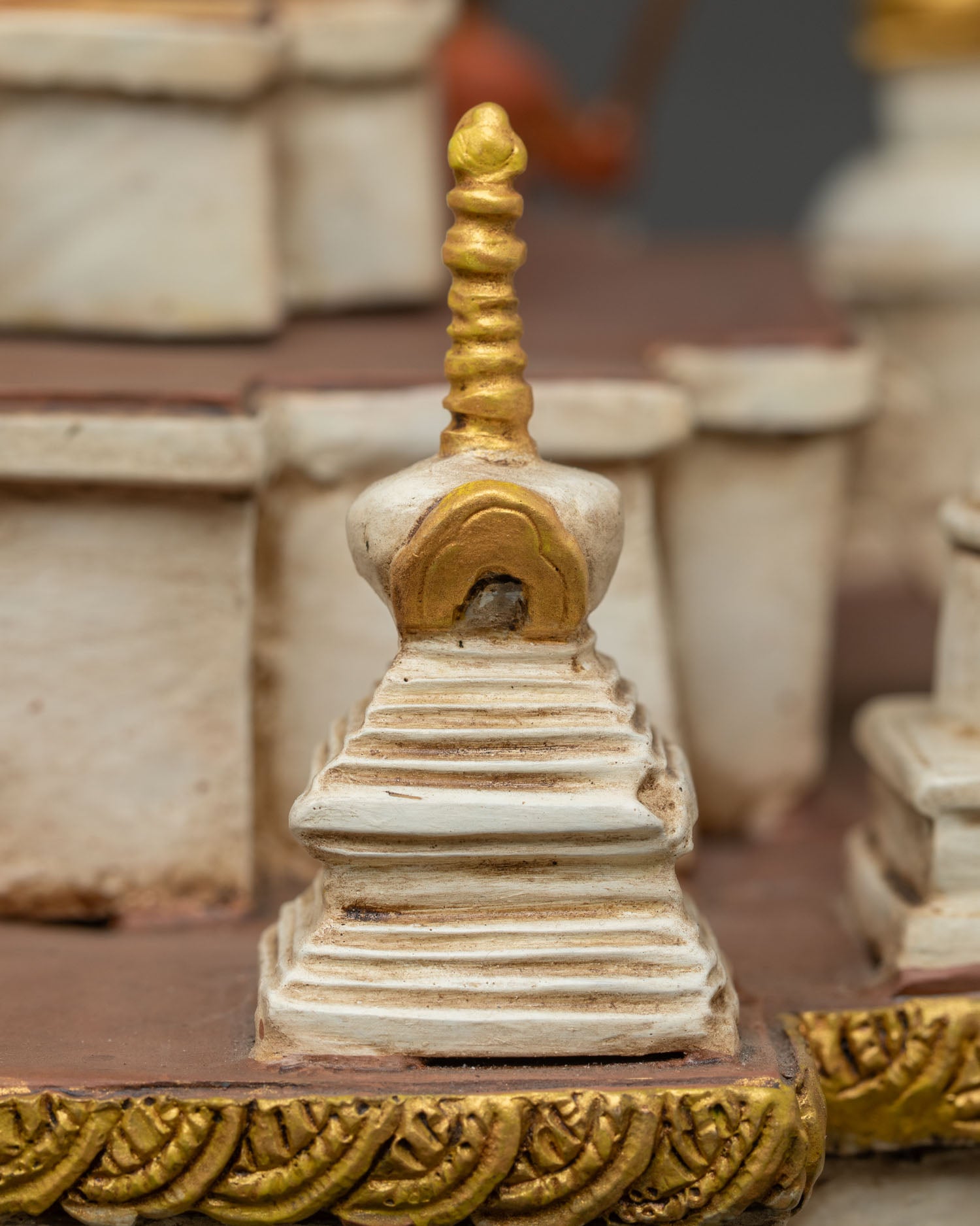 Detailed corner stupa with gold pinnacle on miniature Boudha monument
