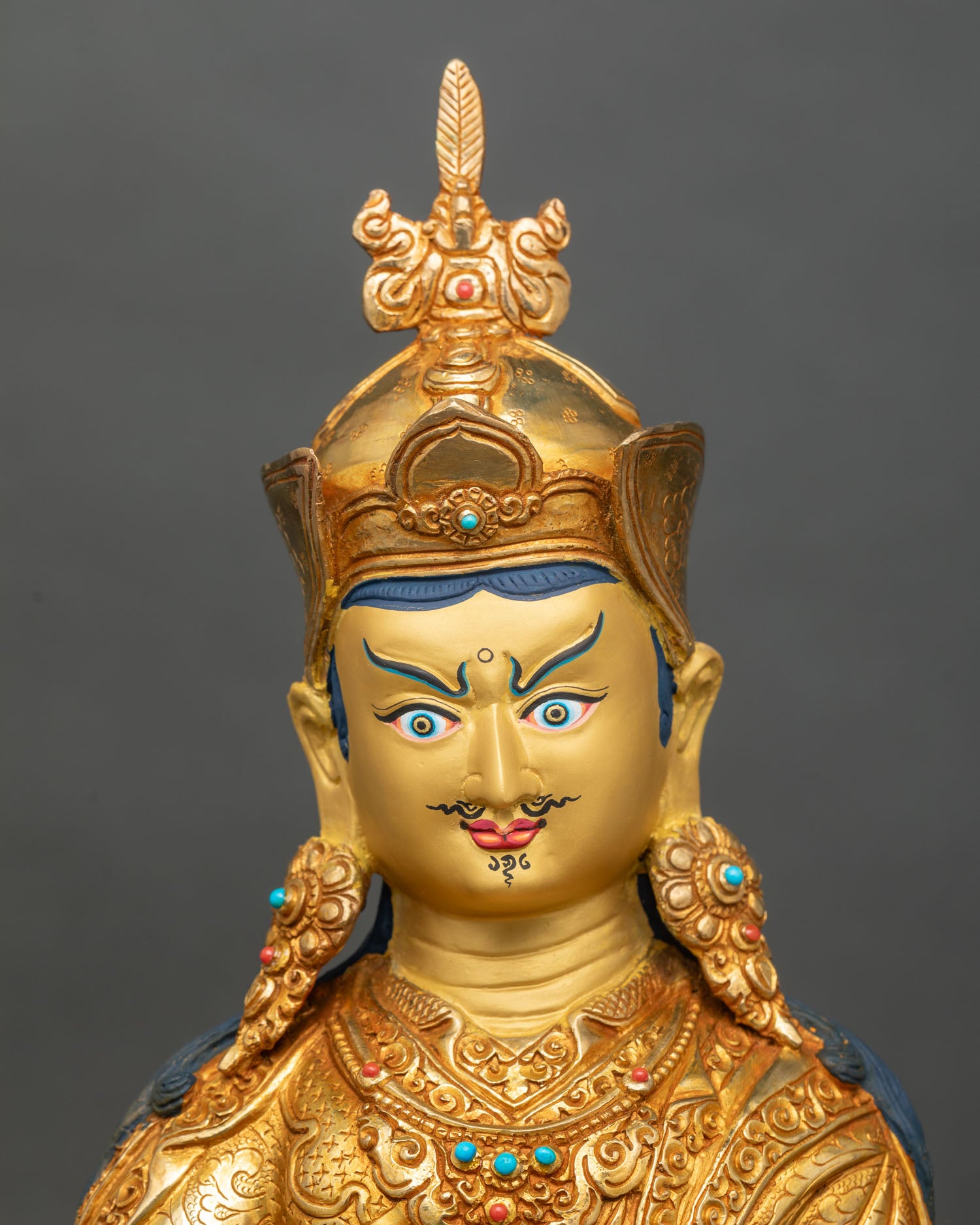 Detailed face close-up of Guru Rinpoche, intricate copper and gold features