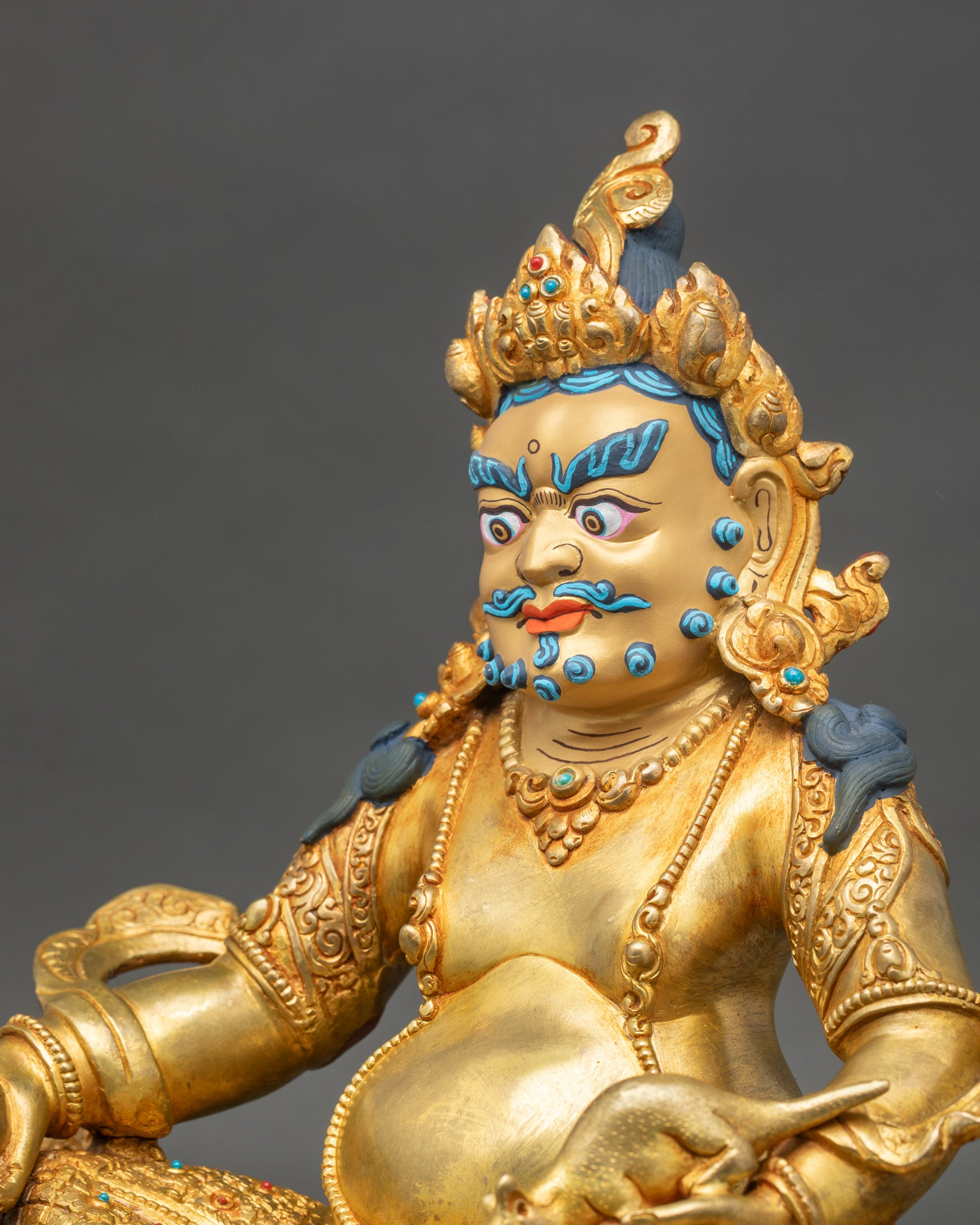 Detailed side close-up of Dzambhala statue, intricate jewelry and lotus pedestal