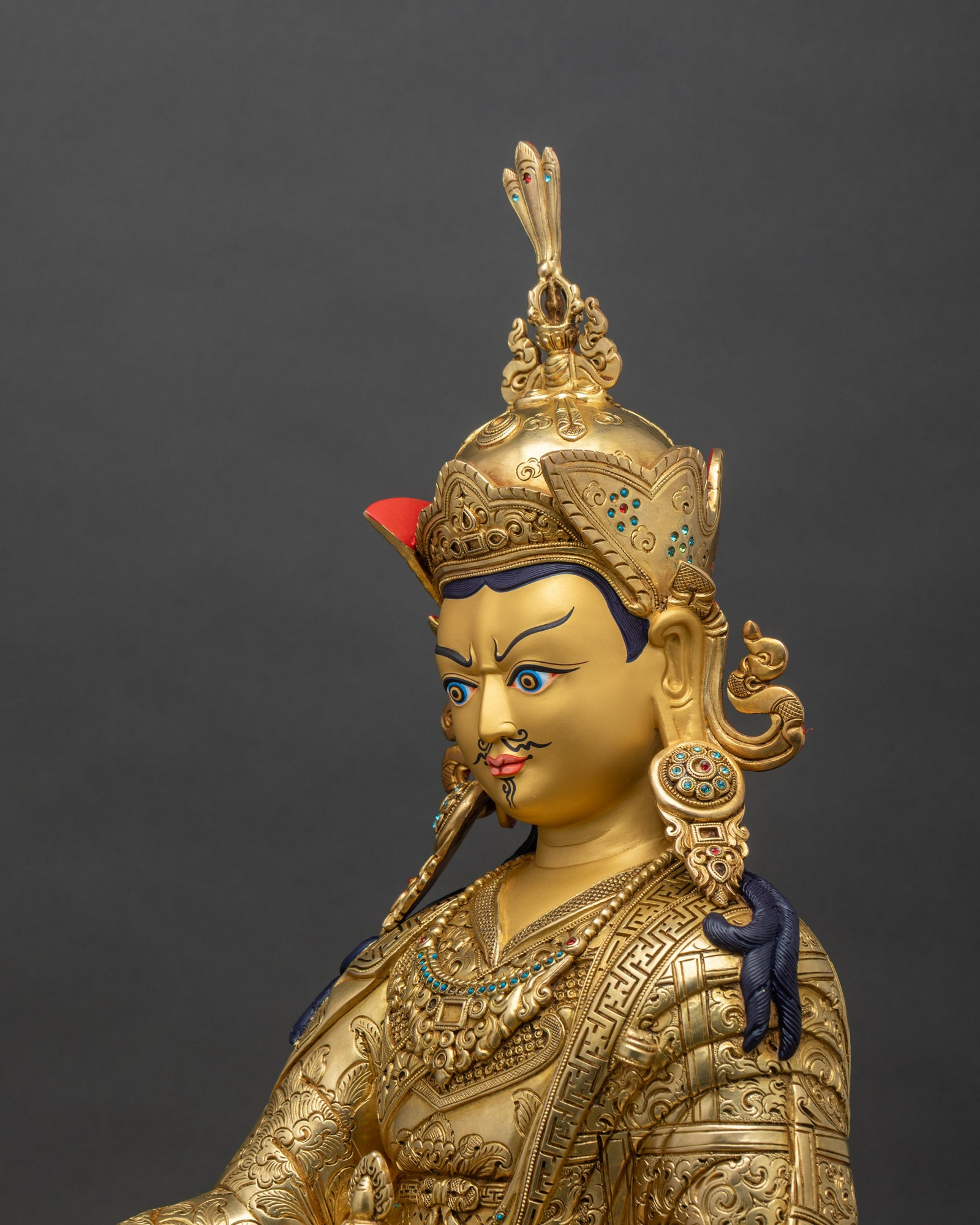 Detailed side close-up of Guru Rinpoche statue with ornate robes and lotus throne