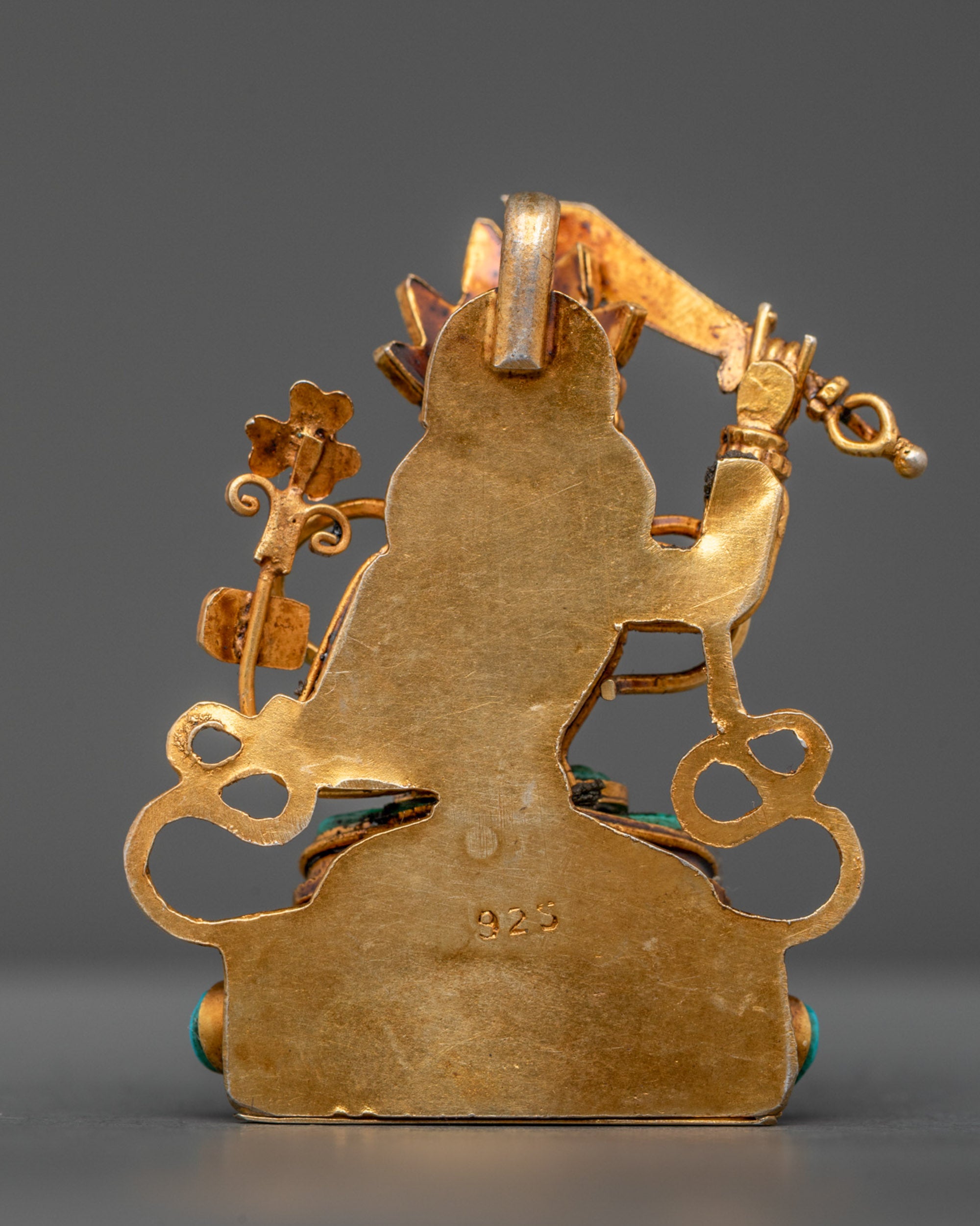 Detailed back view of gold-gilded Manjushri amulet with artisan carvings