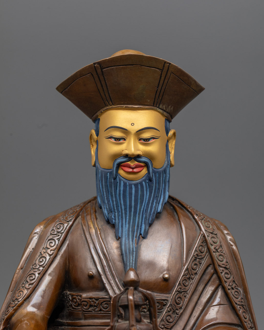 Detailed carving of Guru Shapdum statue’s chögu robe and pandit hat crafted using traditional lost wax method