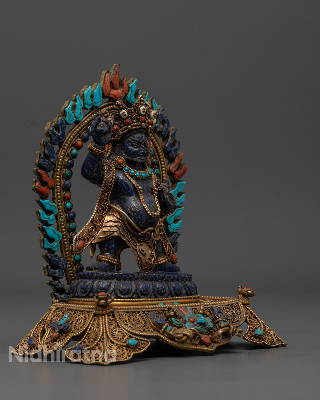 Detailed carving on Vajrapani statue featuring flowing robe decorated with turquoise, coral, and lapis lazuli stones

