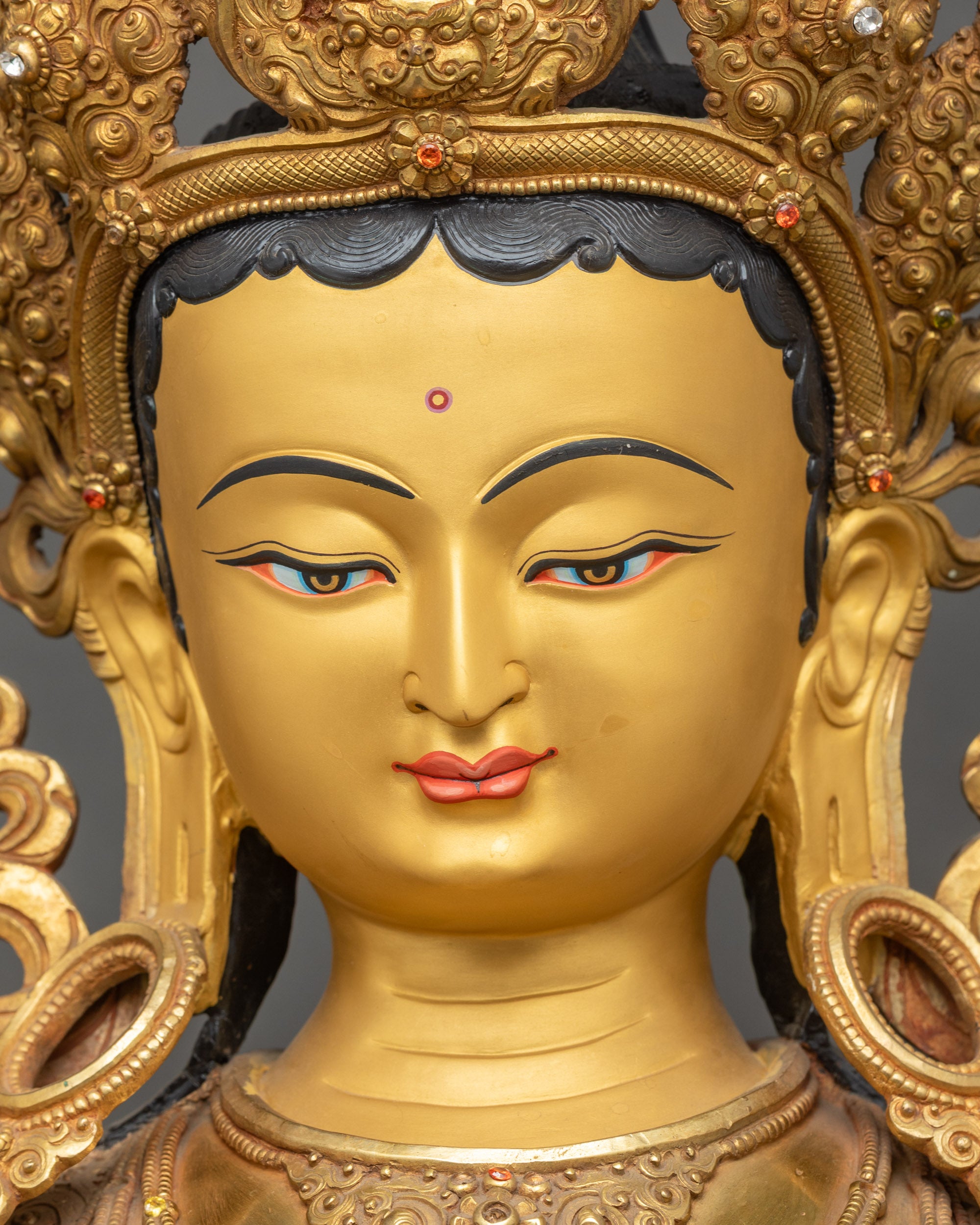 Detailed close-up face of Green Tara statue with serene expression and gold fire-gilding