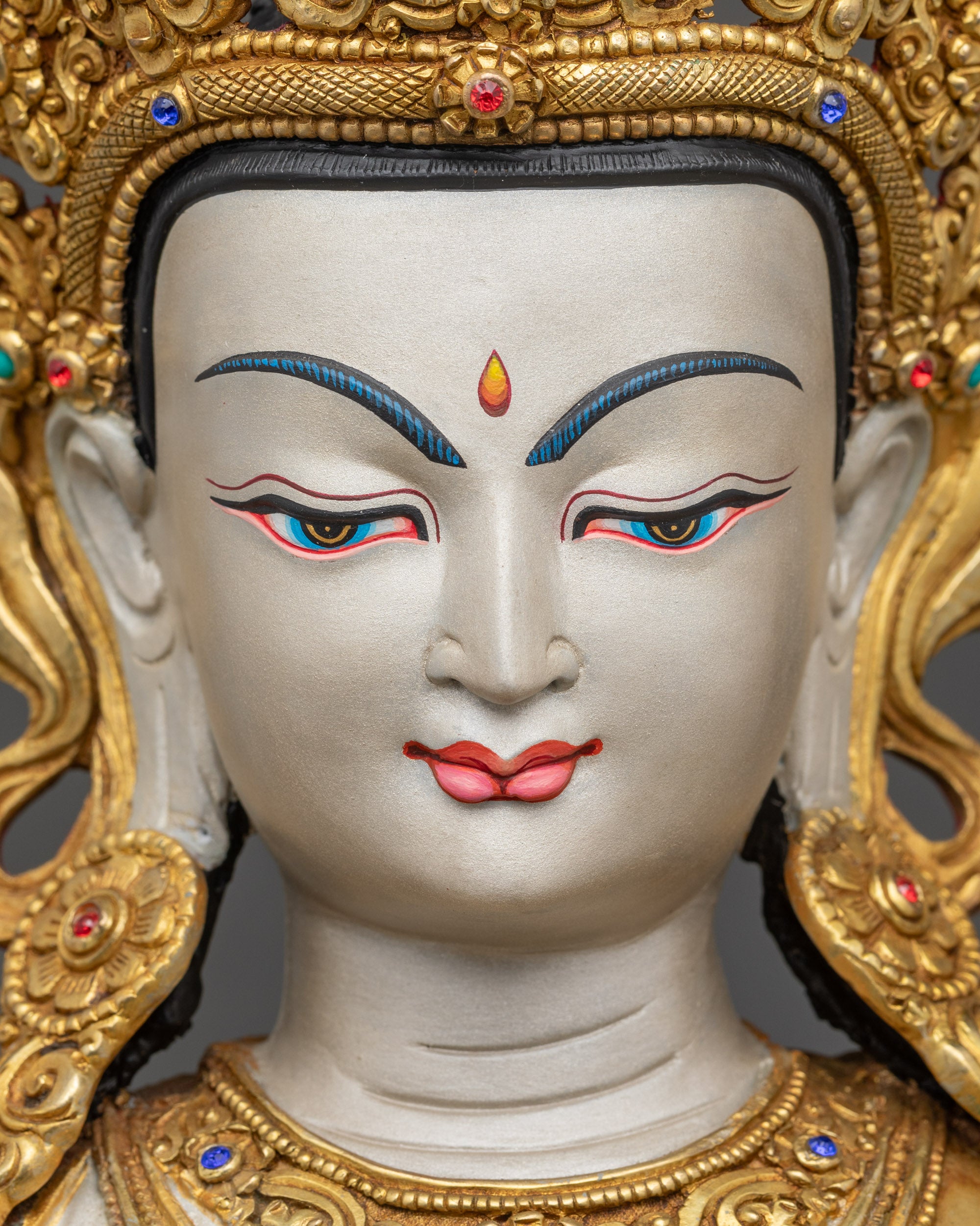 Detailed close-up of Chenrezig Statue face, serene expression with gold-gilded crown features