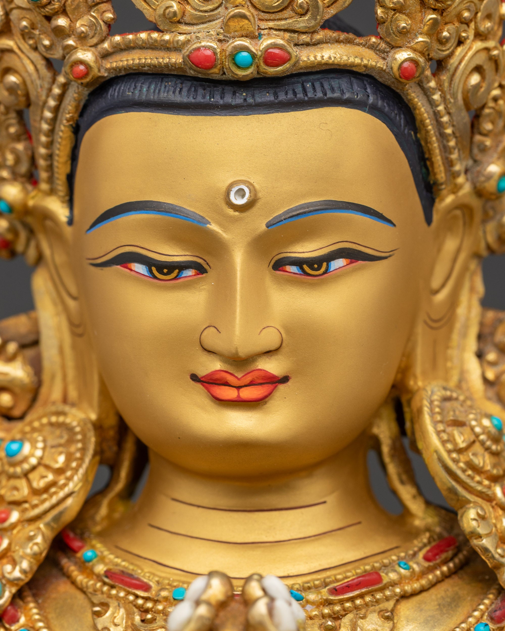 Detailed close-up of Chenrezig statue face highlighting gilded features and serene expression