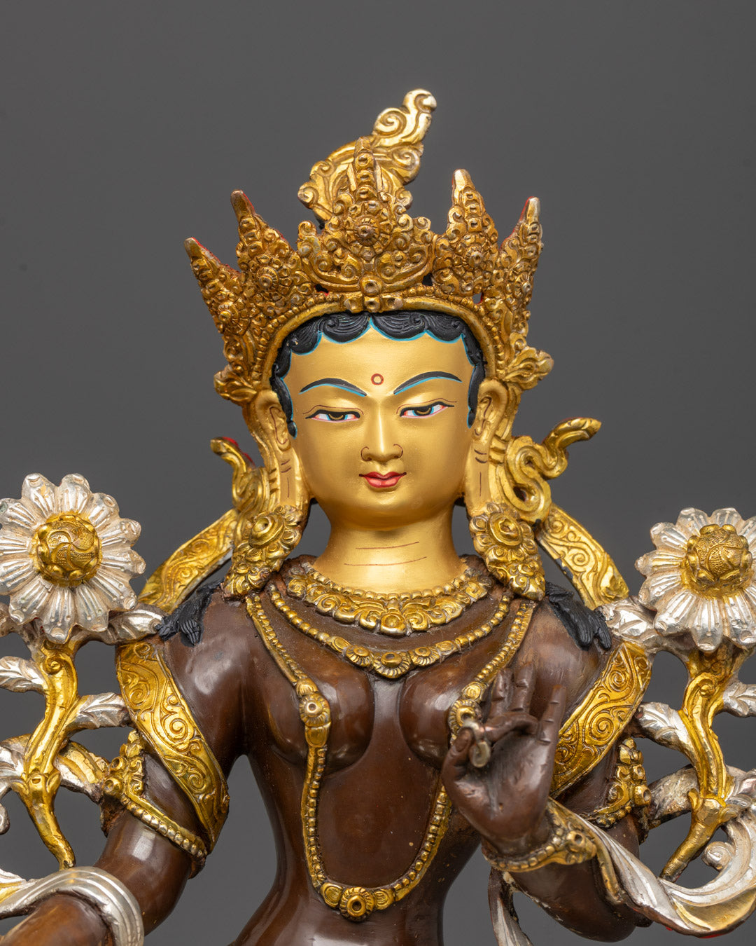 Detailed close-up of Green Tara's serene face with radiant gold finish