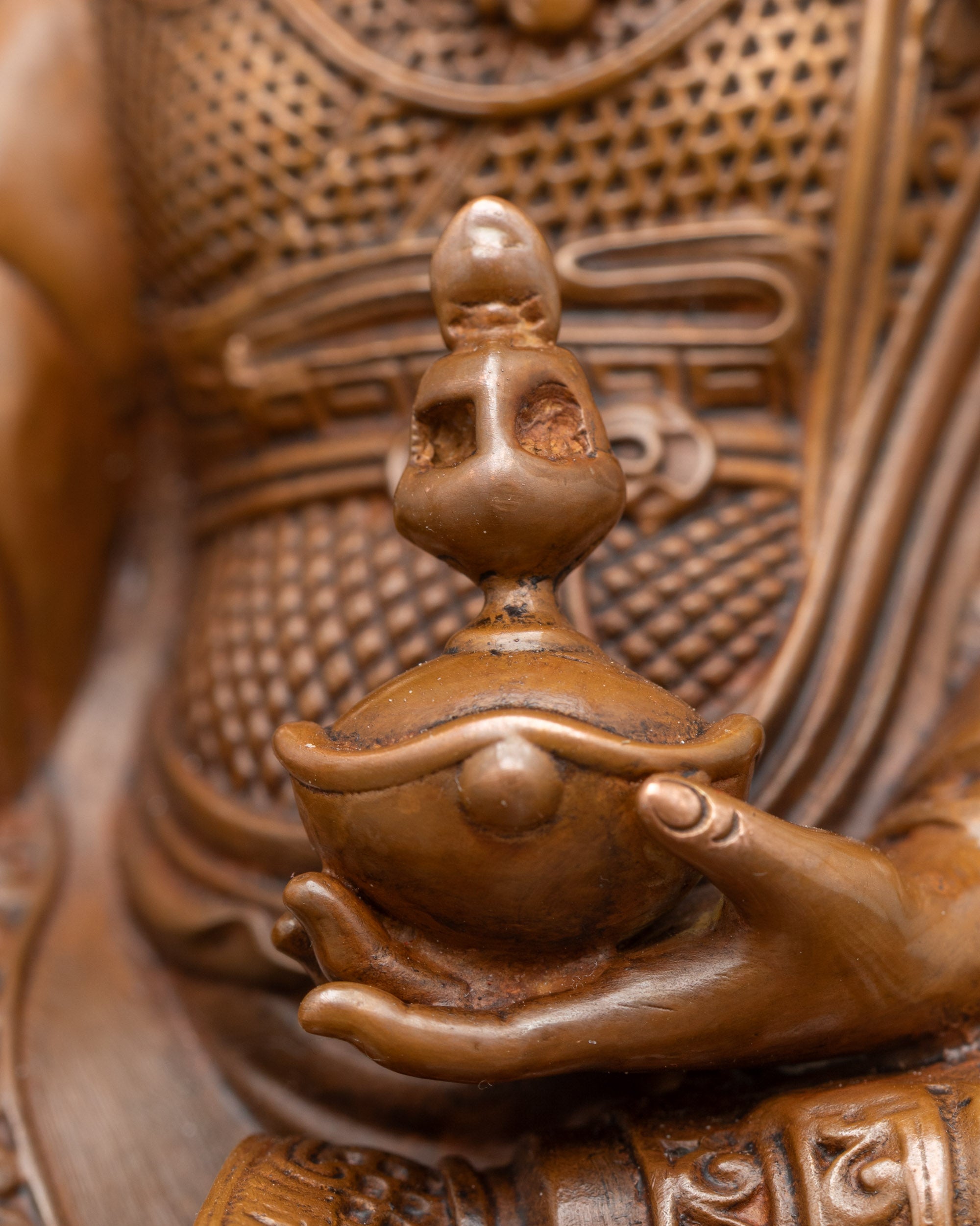 Detailed close-up of Guru Rinpoche’s vajra and skull cup on oxidised Himalayan statue