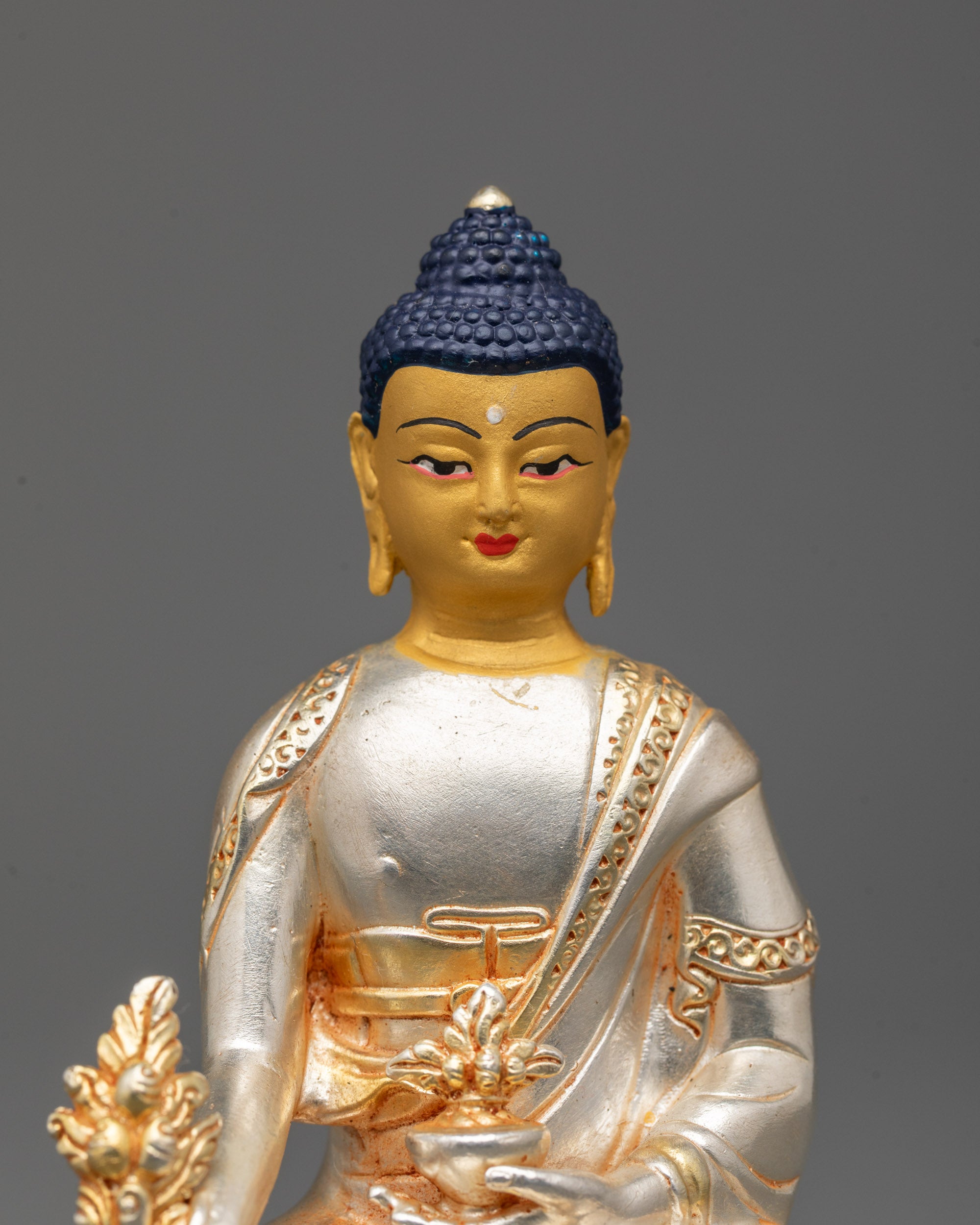 Detailed close-up of Medicine Buddha's 24k gold-painted face showcasing serene expression
