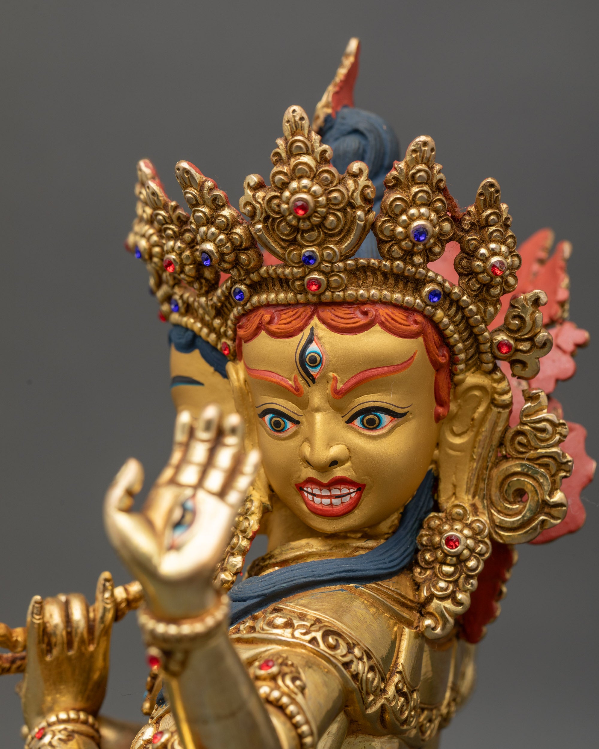 Detailed close-up of Namgyalma statue face with three expressions, gold-painted visage