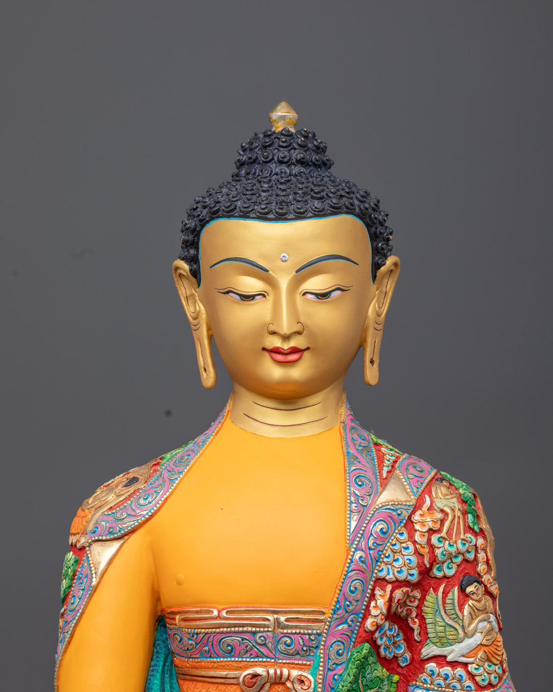 Shakyamuni Buddha’s serene face with gold gilding and vibrant yellow acrylic highlights on copper statue.