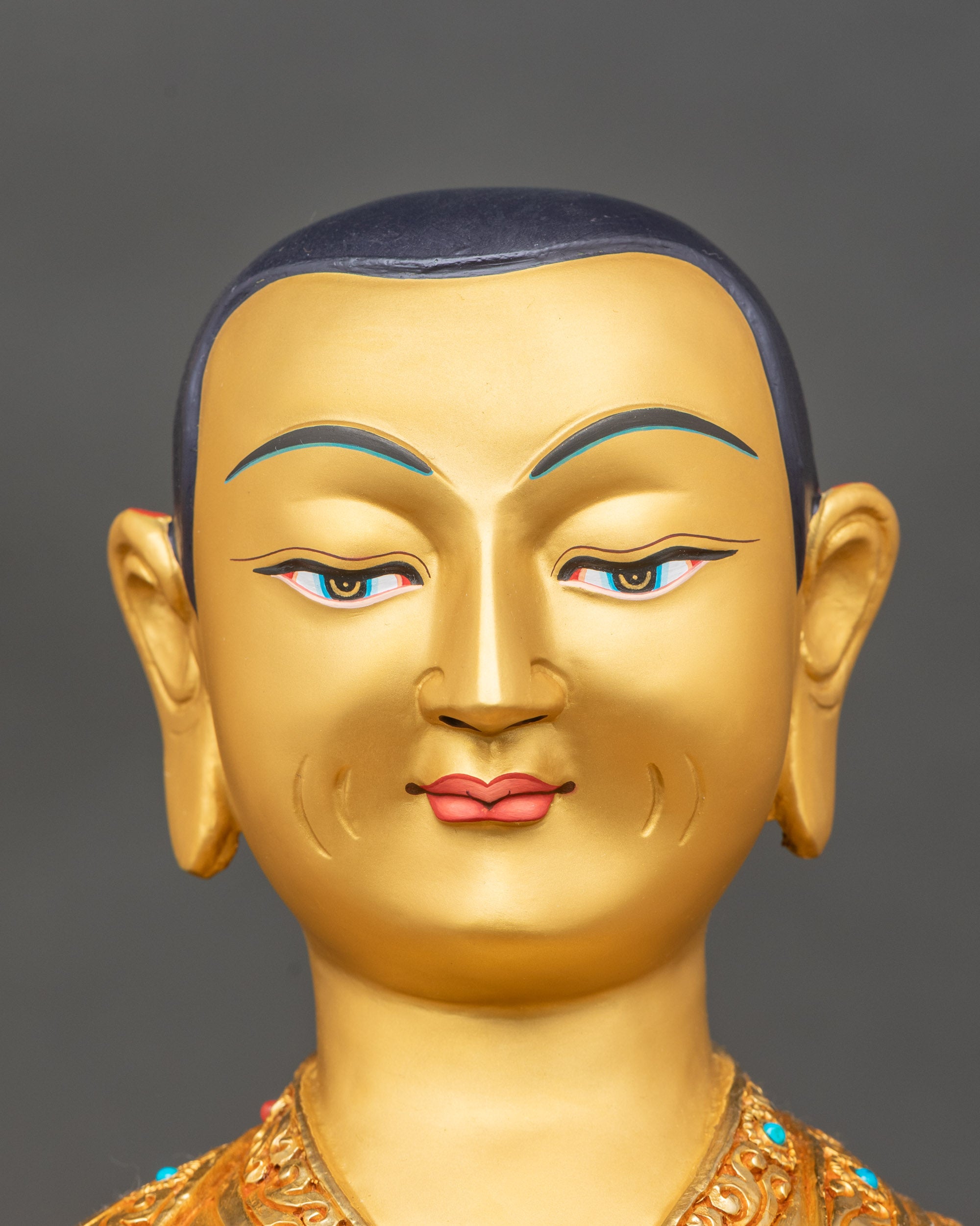 Detailed close-up of Tsongkhapa face, gold-painted features, peaceful expression