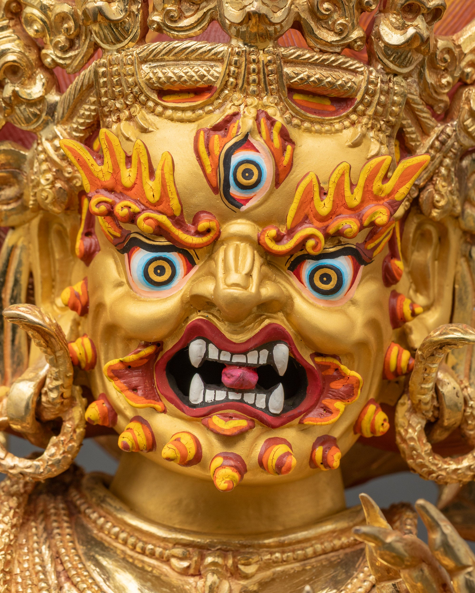Detailed close-up of Vajrapani’s face, gold fire-gilded with expressive Himalayan features
