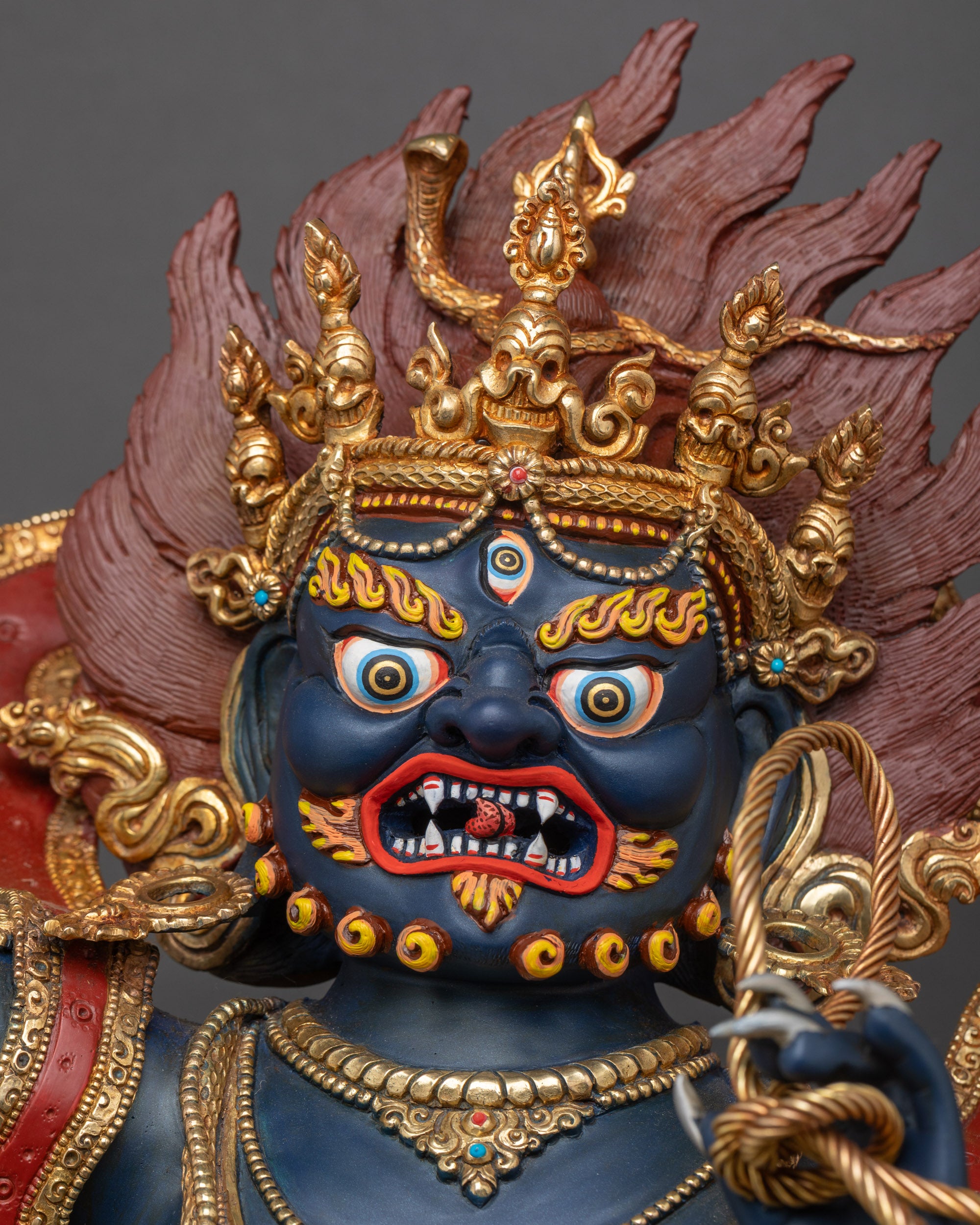Detailed close-up of Vajrapani’s fierce face with piercing eyes, bared fangs, and flaming hair