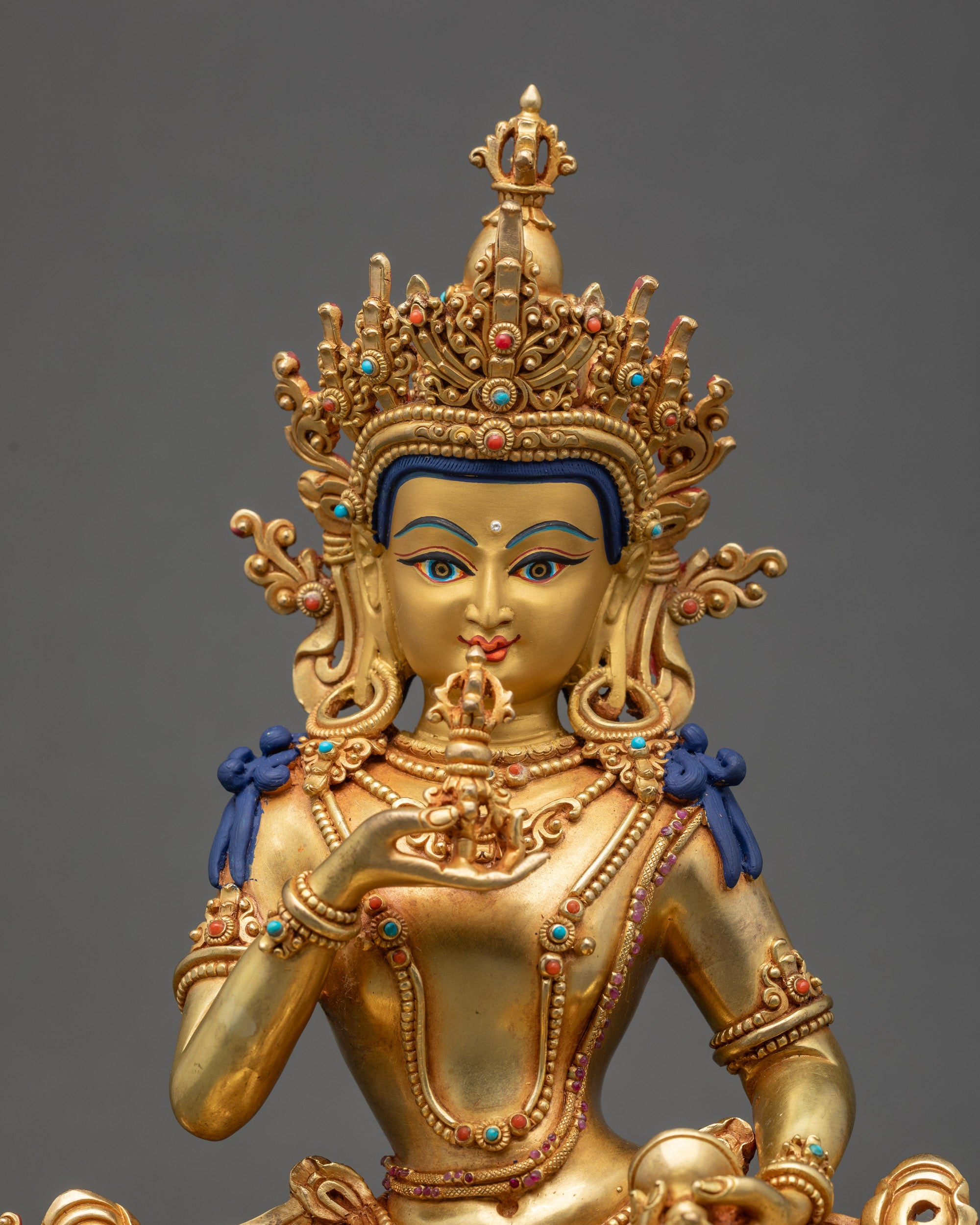 Detailed close-up of Vajrasattva face showing gold paint and intricate 3D carving