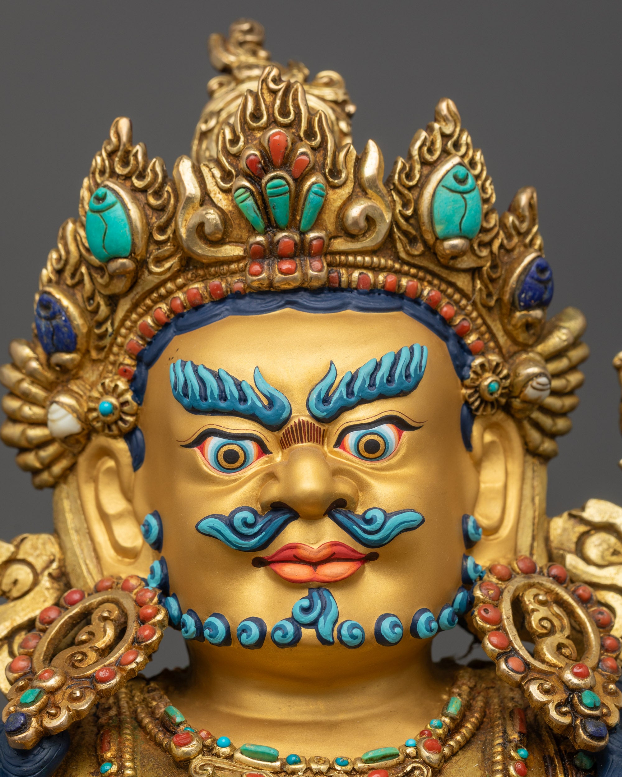 Detailed close up Black Dzambhala statue gold-gilded face with semi-wrathful expression