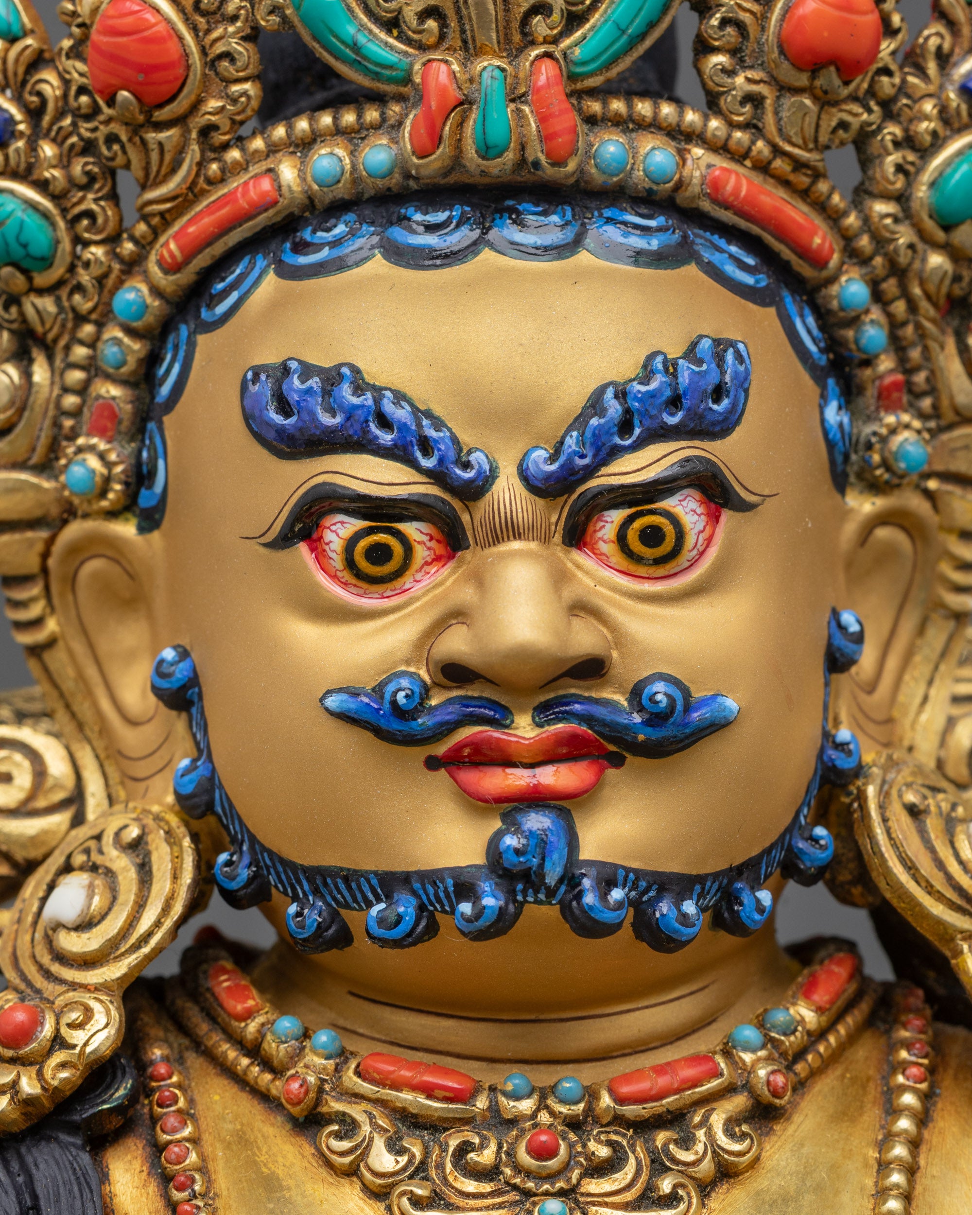 Detailed close up Dzambhala face with blue eyebrows and golden complexion