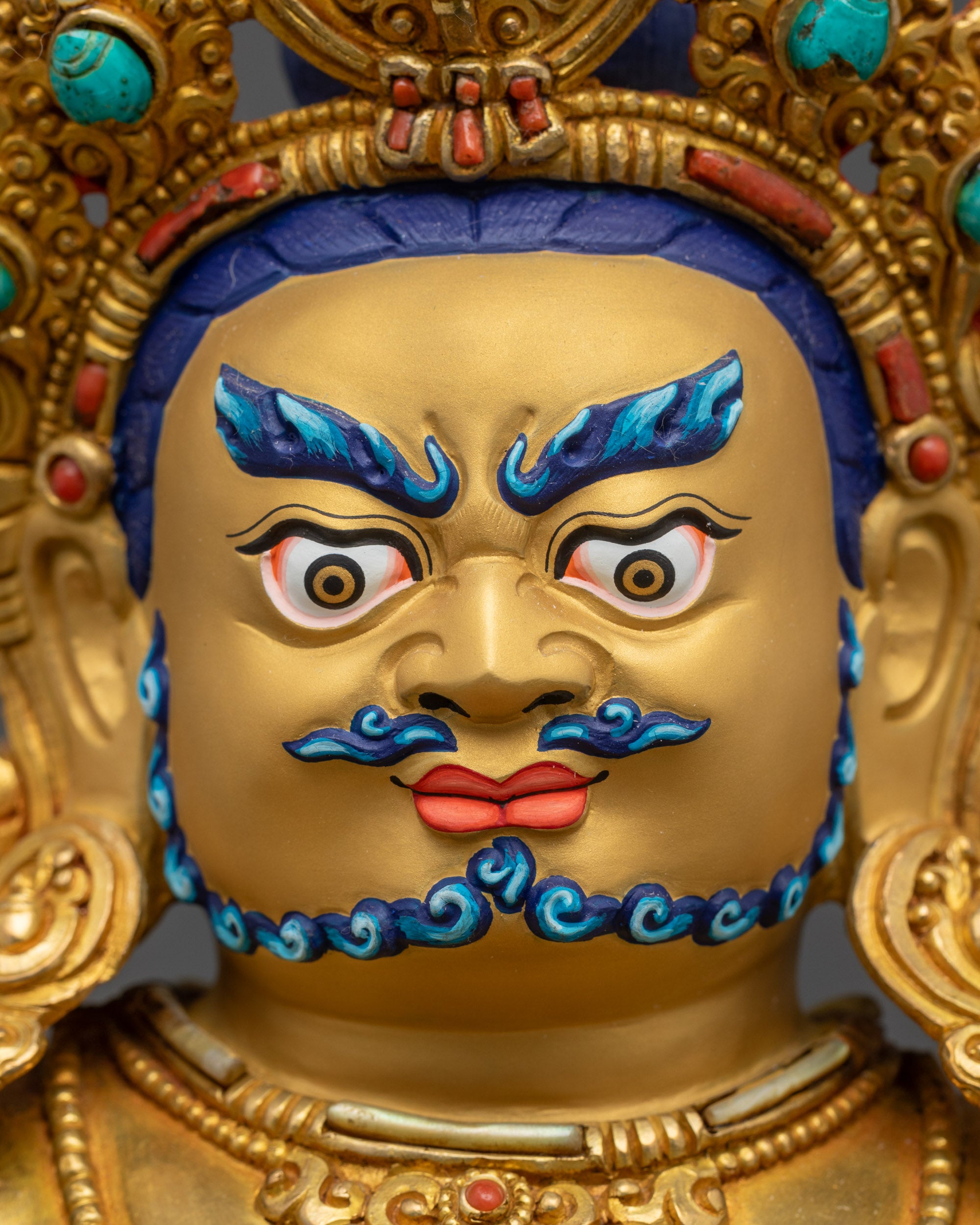 Detailed close up face Dzambhala wrathful expression with five-jeweled crown and intricately carved jewelry
