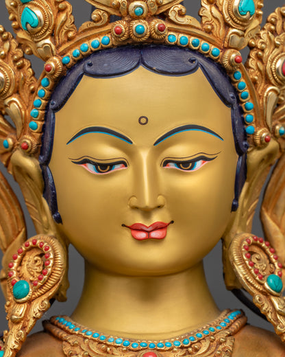 Detailed close up face Green Tara gold-gilded serene expression with crown and jewelry