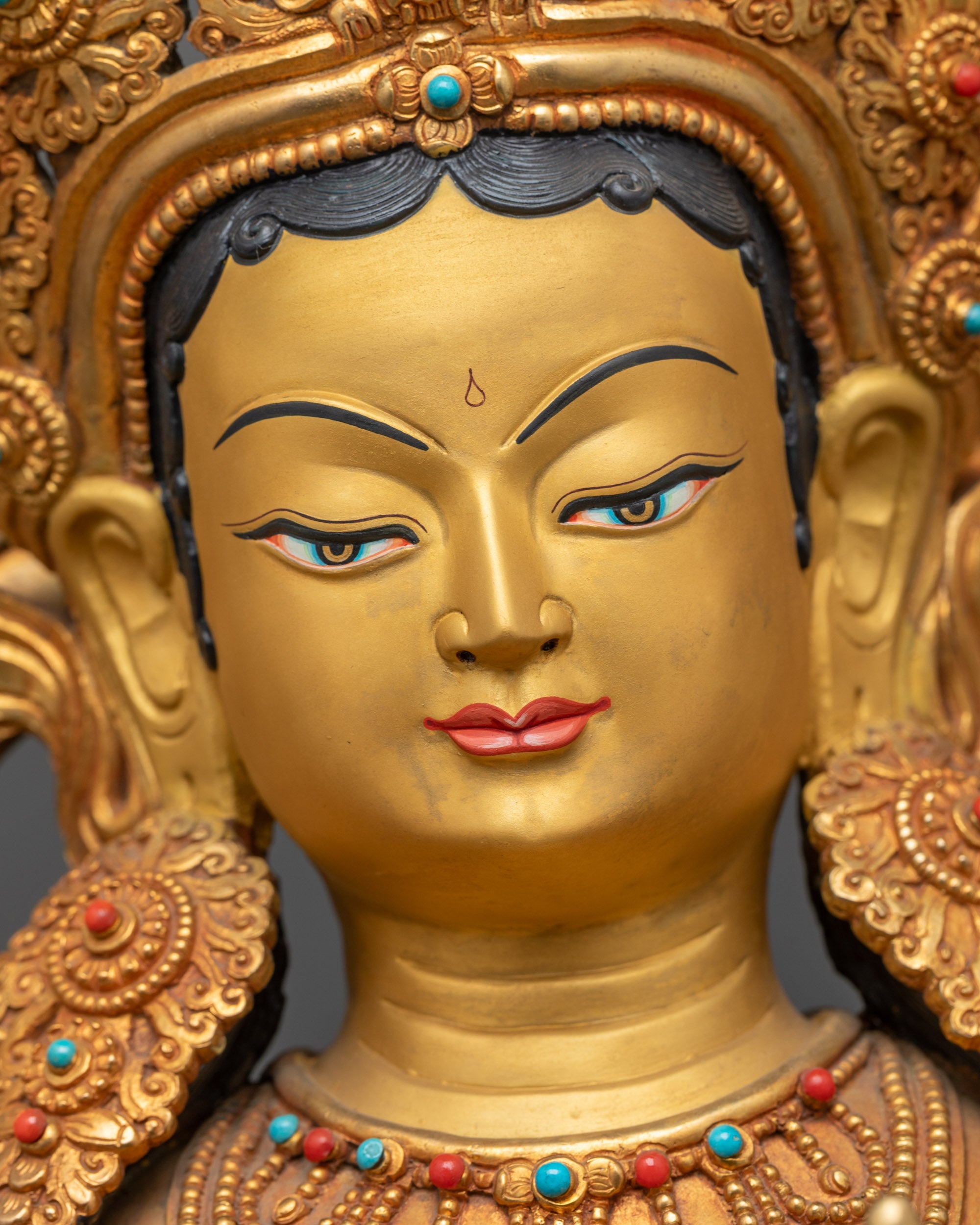 Detailed close up face Green Tara serene gold-gilded face crown semi-precious stones
