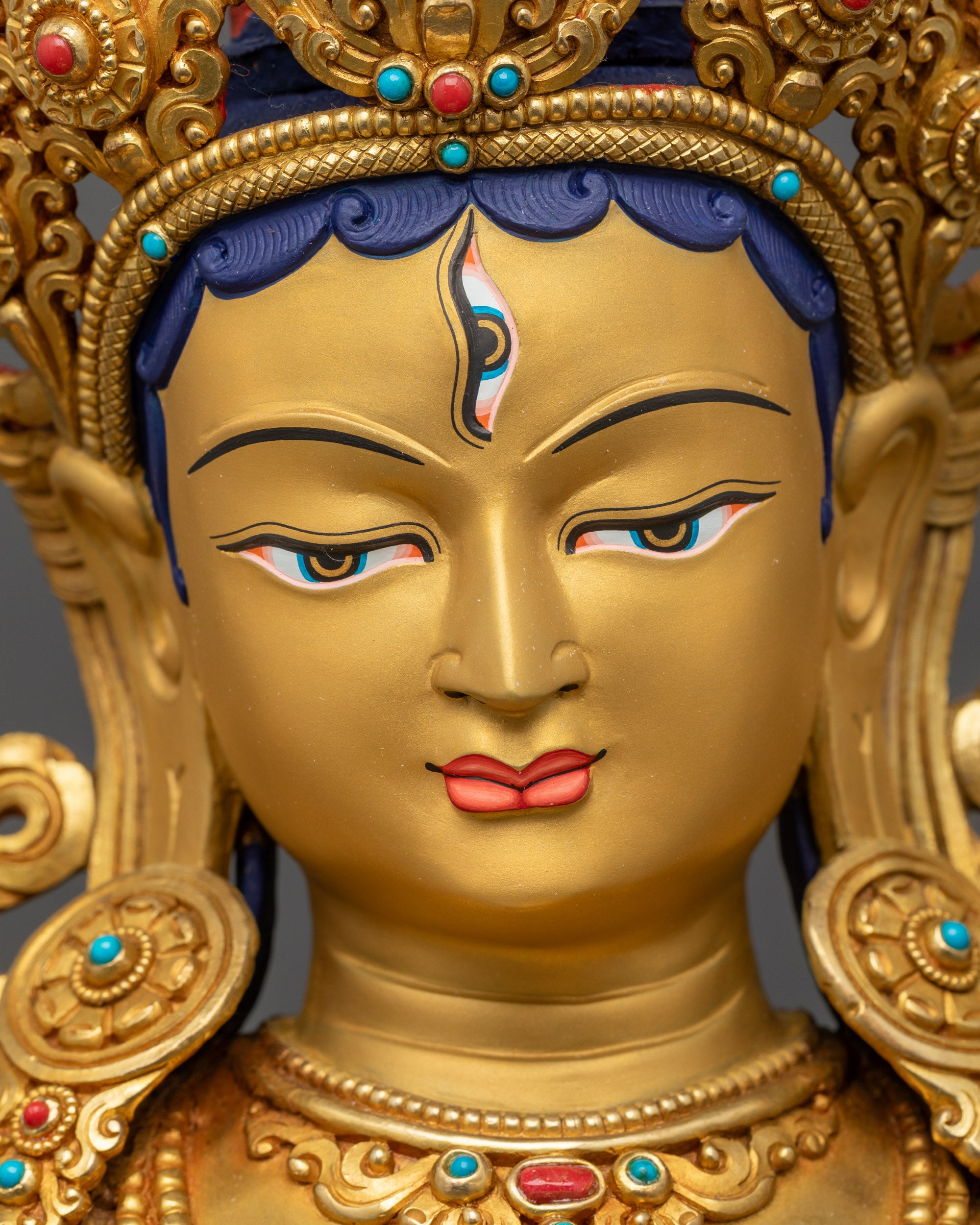 Detailed close up face White Tara Statue with tranquil gold-gilded expression
