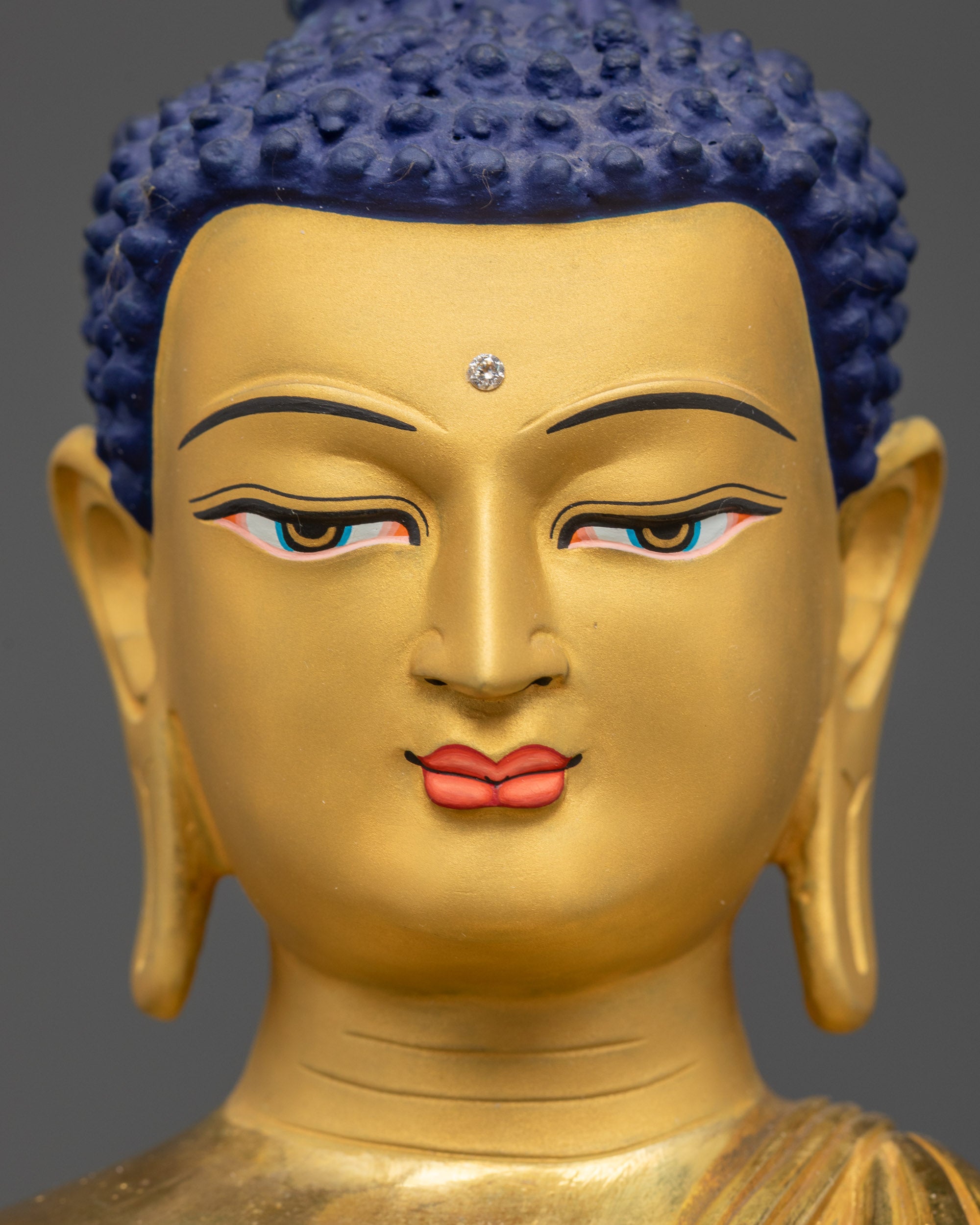Detailed close up face of Amitabha Buddha Nepalese artisan statue with 24K gold gilding
