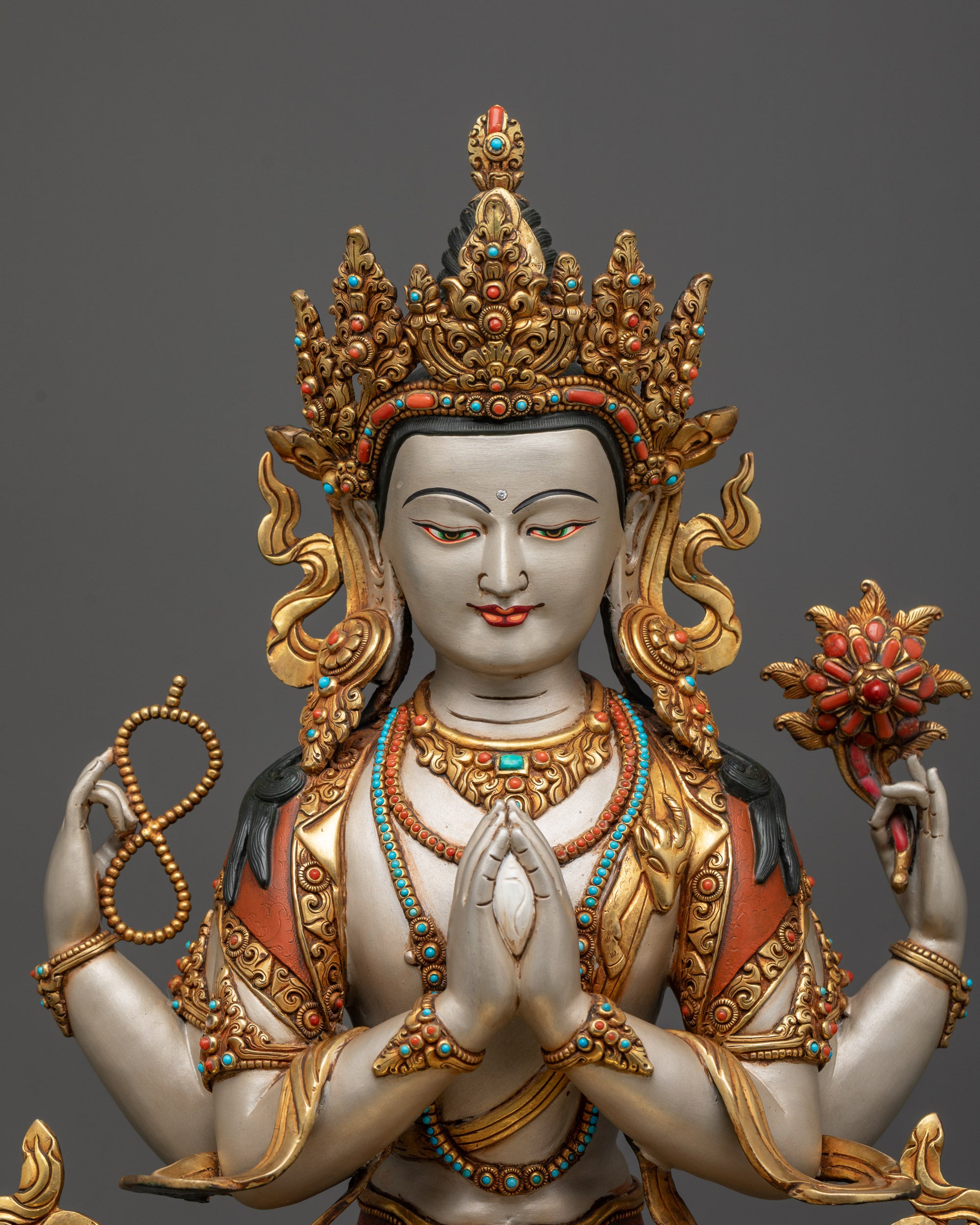 Regular close up Chenrezig statue showing four arms and symbolic treasures
