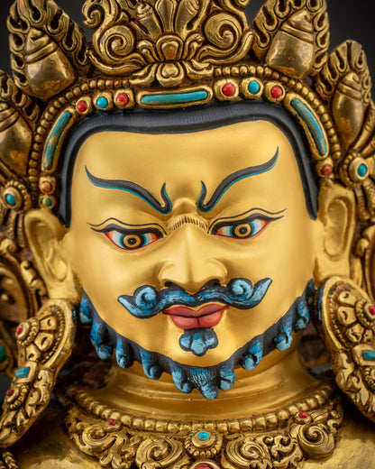 Detailed close up face of Dzambhala statue showing piercing eyes and blue eyebrows
