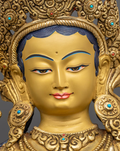 Detailed close up face of Green Tara Statue with tranquil gold-gilded expression
