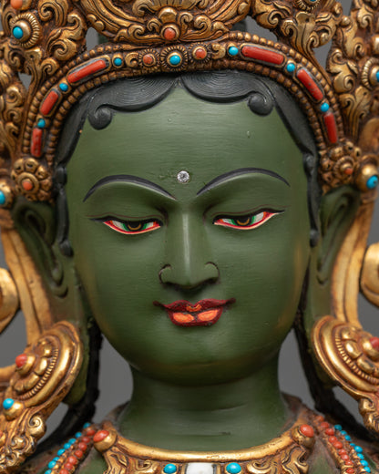 Detailed close up face of Green Tara statue with semi-precious crown and serene expression
