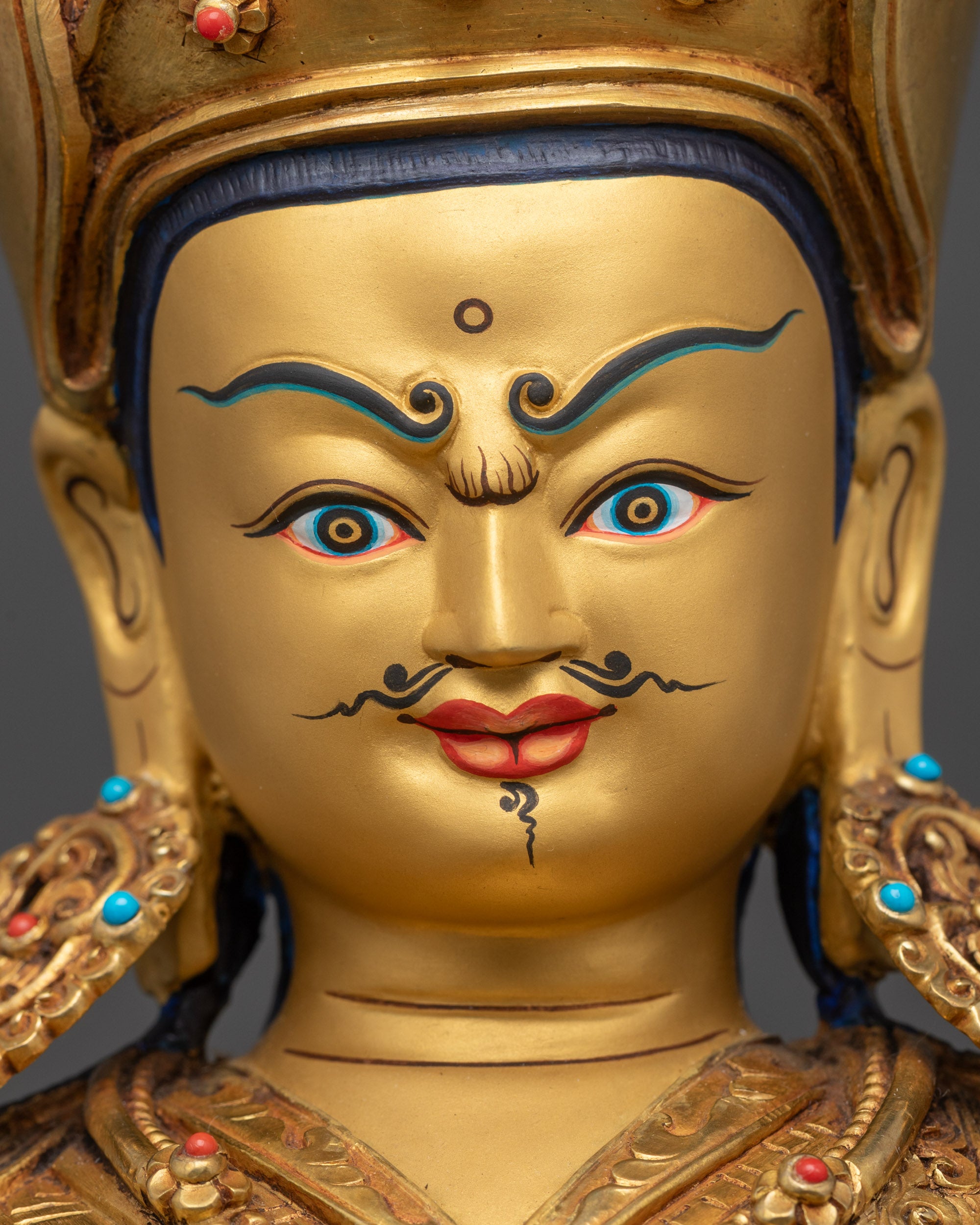 Detailed close up face of Guru Rinpoche statue showing wrathful yet calm expression
