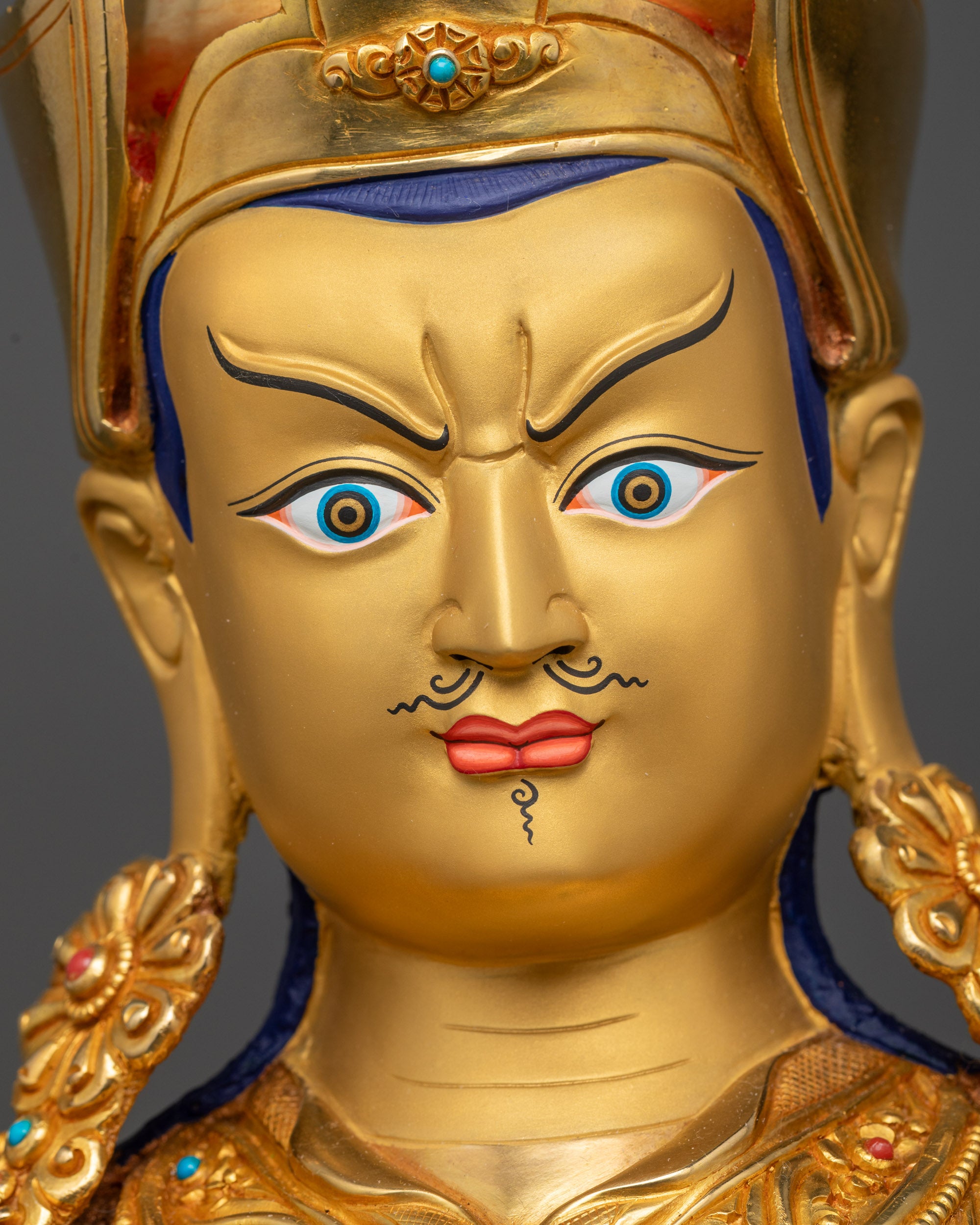 Detailed close up face of Guru Rinpoche statue with skull cup and Dorje
