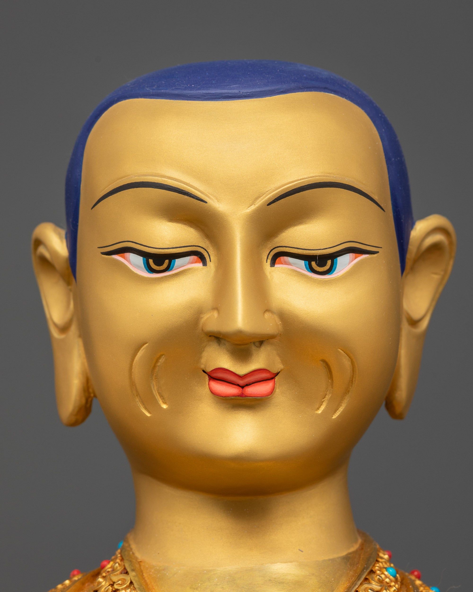 Detailed close up face of Je Tsongkhapa showing carved robe and semi-precious stones
